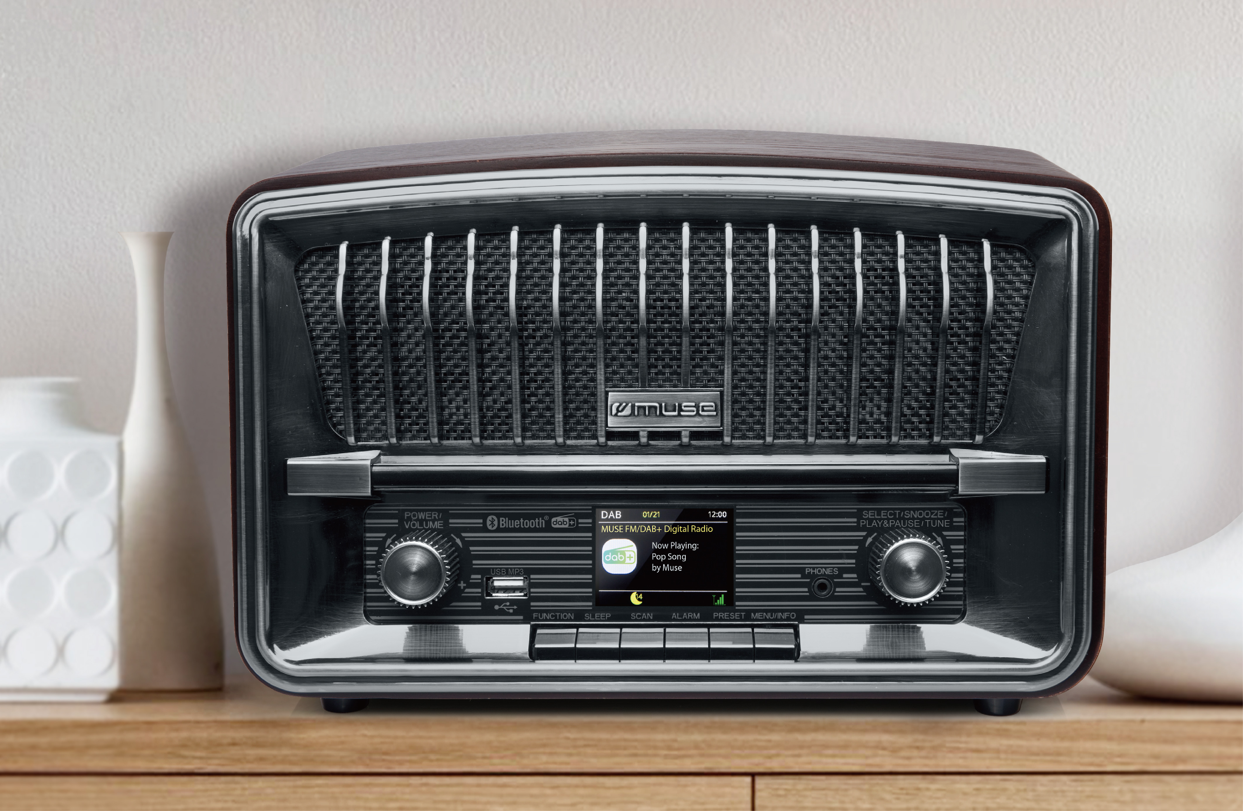 Radio de estilo retro sobre una superficie de madera, con jarrones blancos.