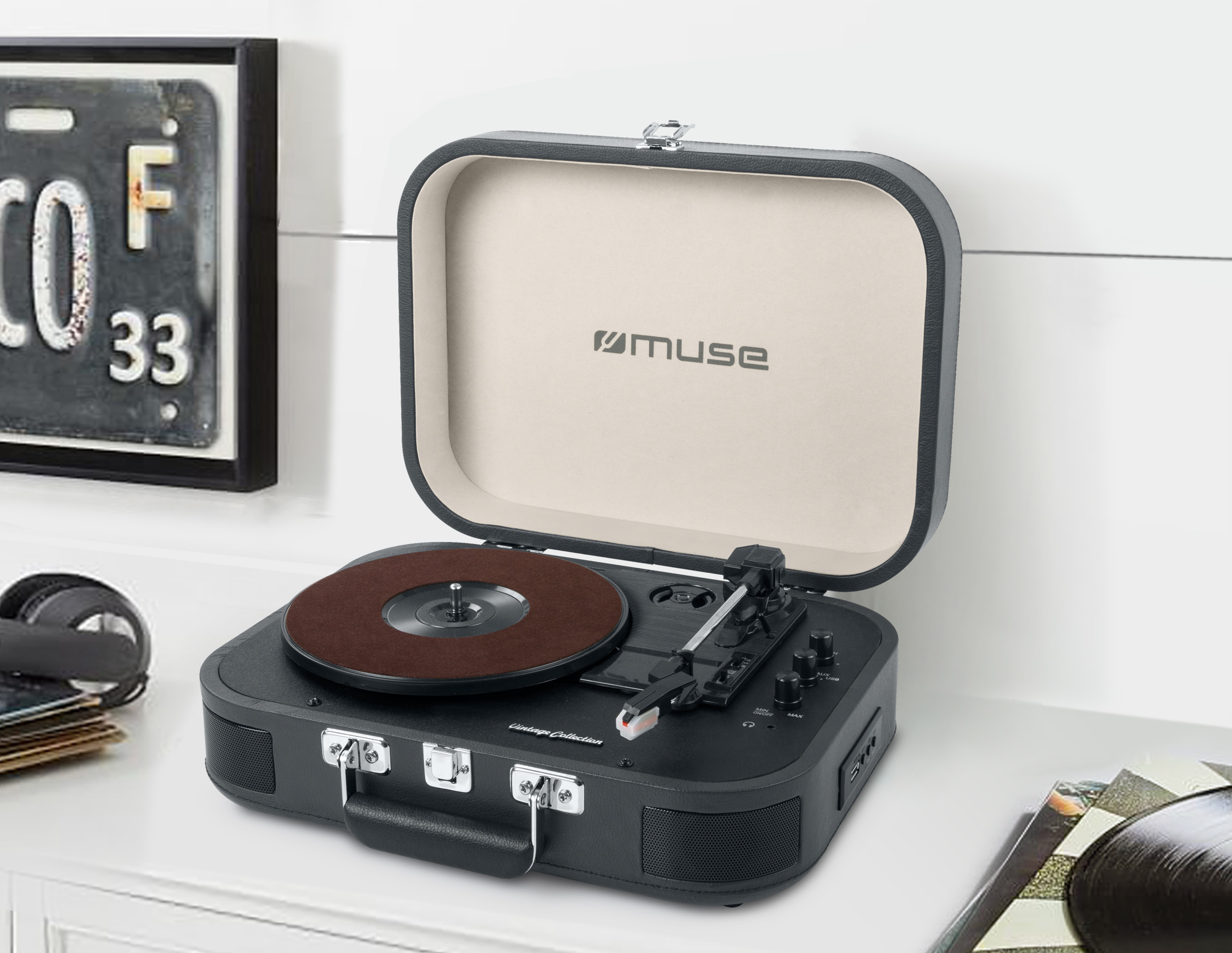 Giradischi in stile vintage con un disco in vinile marrone, aperto su una superficie bianca.