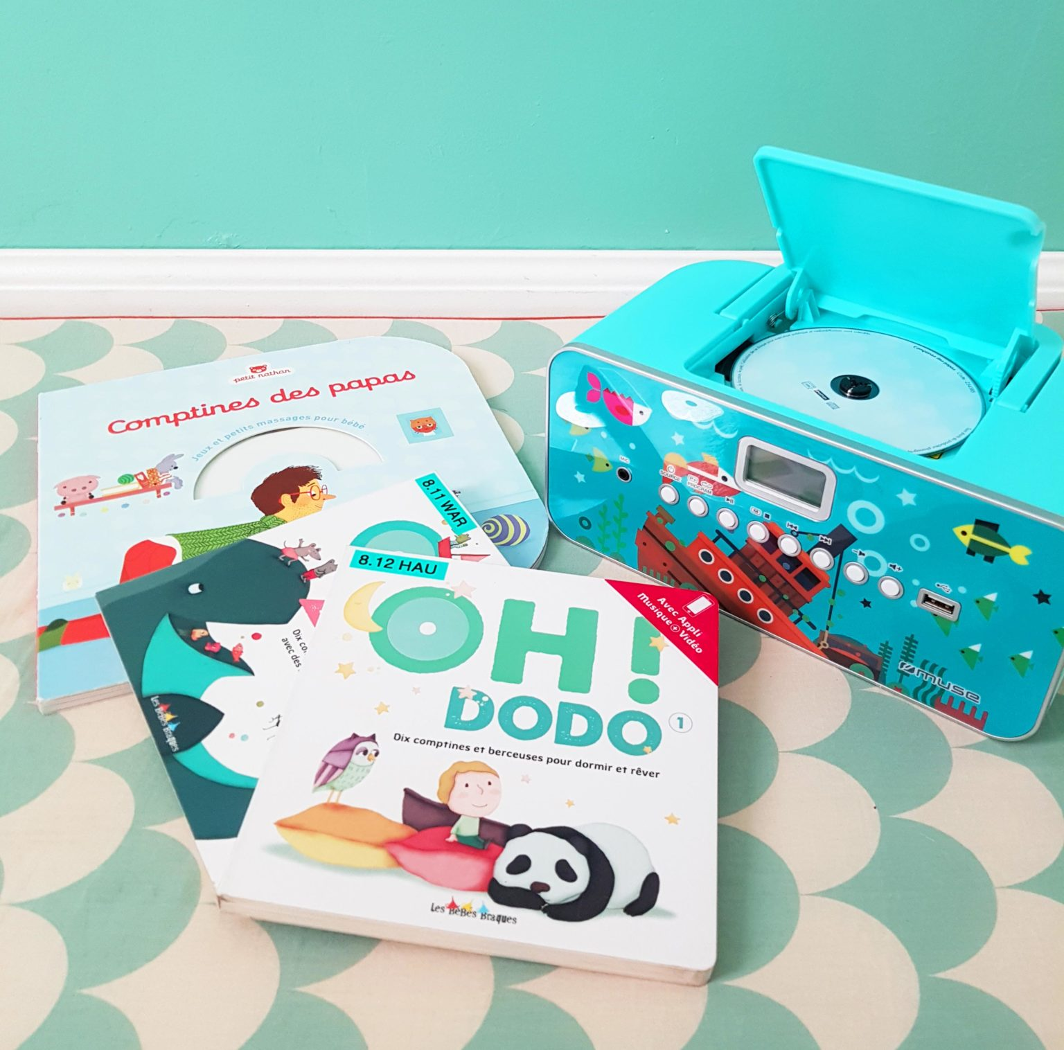 Livres et un lecteur CD bleu avec un disque à l'intérieur. Le tout sur une surface à motifs.