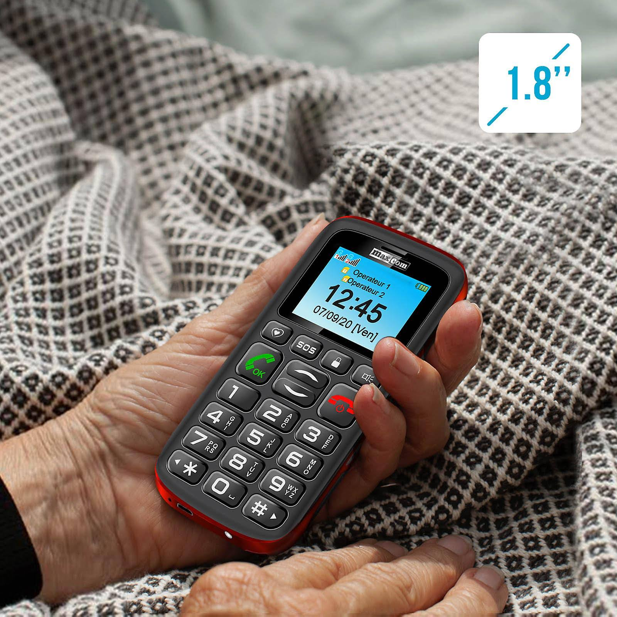 Eine Person hält ein schwarz-rotes Mobiltelefon. Es hat große Tasten und einen Bildschirm.
