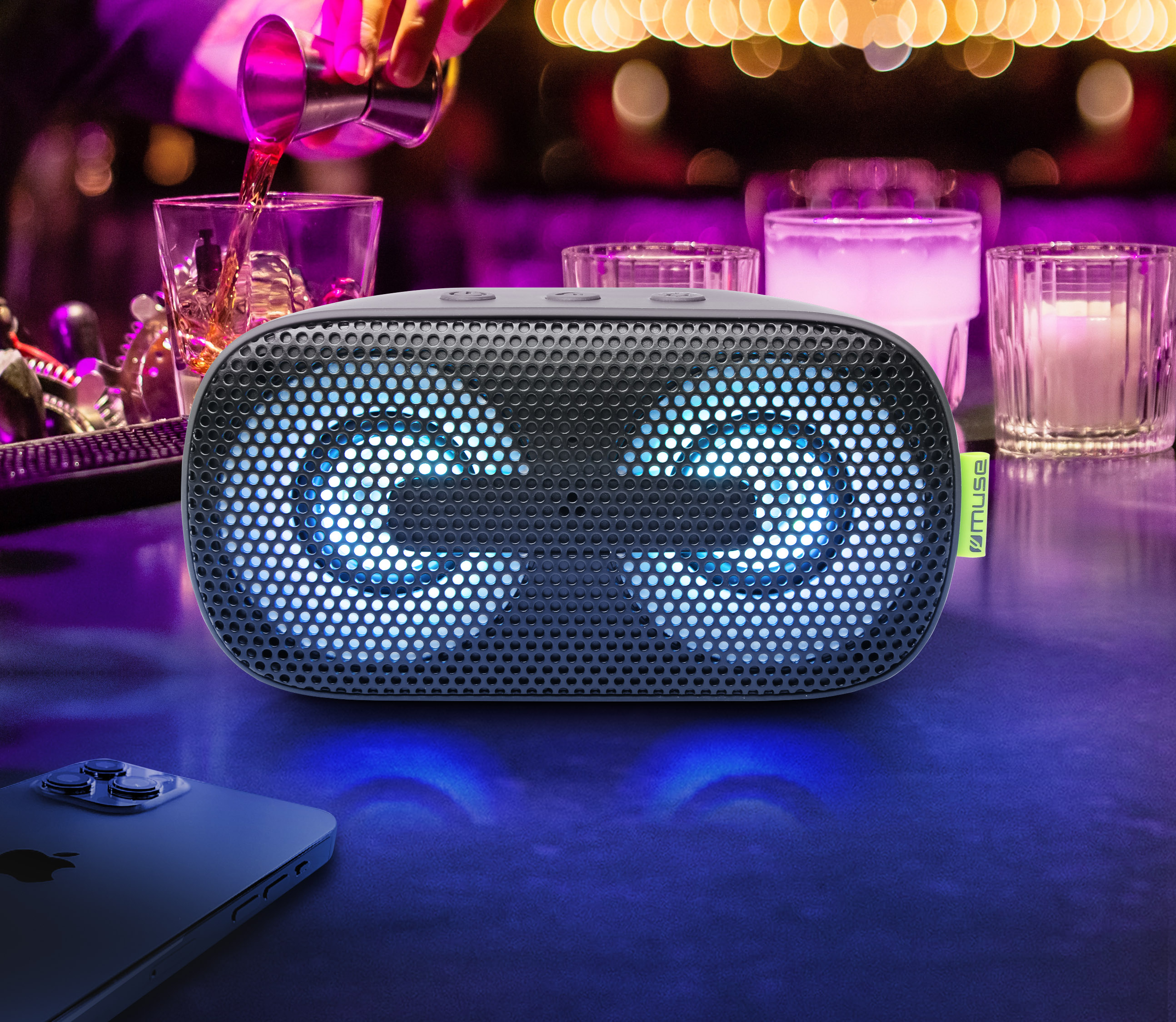 Czarny głośnik z niebieskimi światłami i telefonem. Alkohol wlewa się do szklanki. Scena z baru.