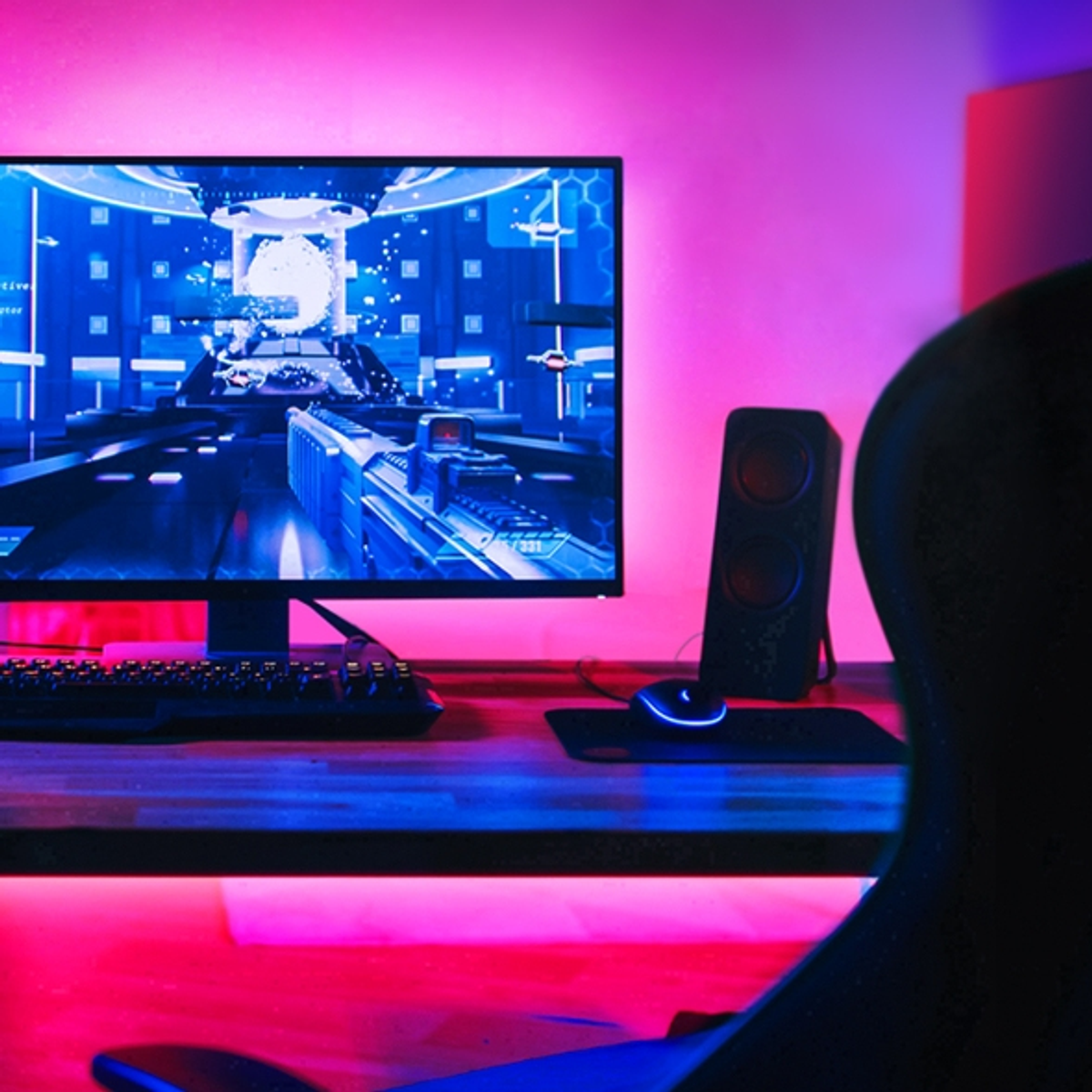 Un setup di gioco con un monitor che mostra un gioco, una tastiera, un mouse e un altoparlante su una scrivania.