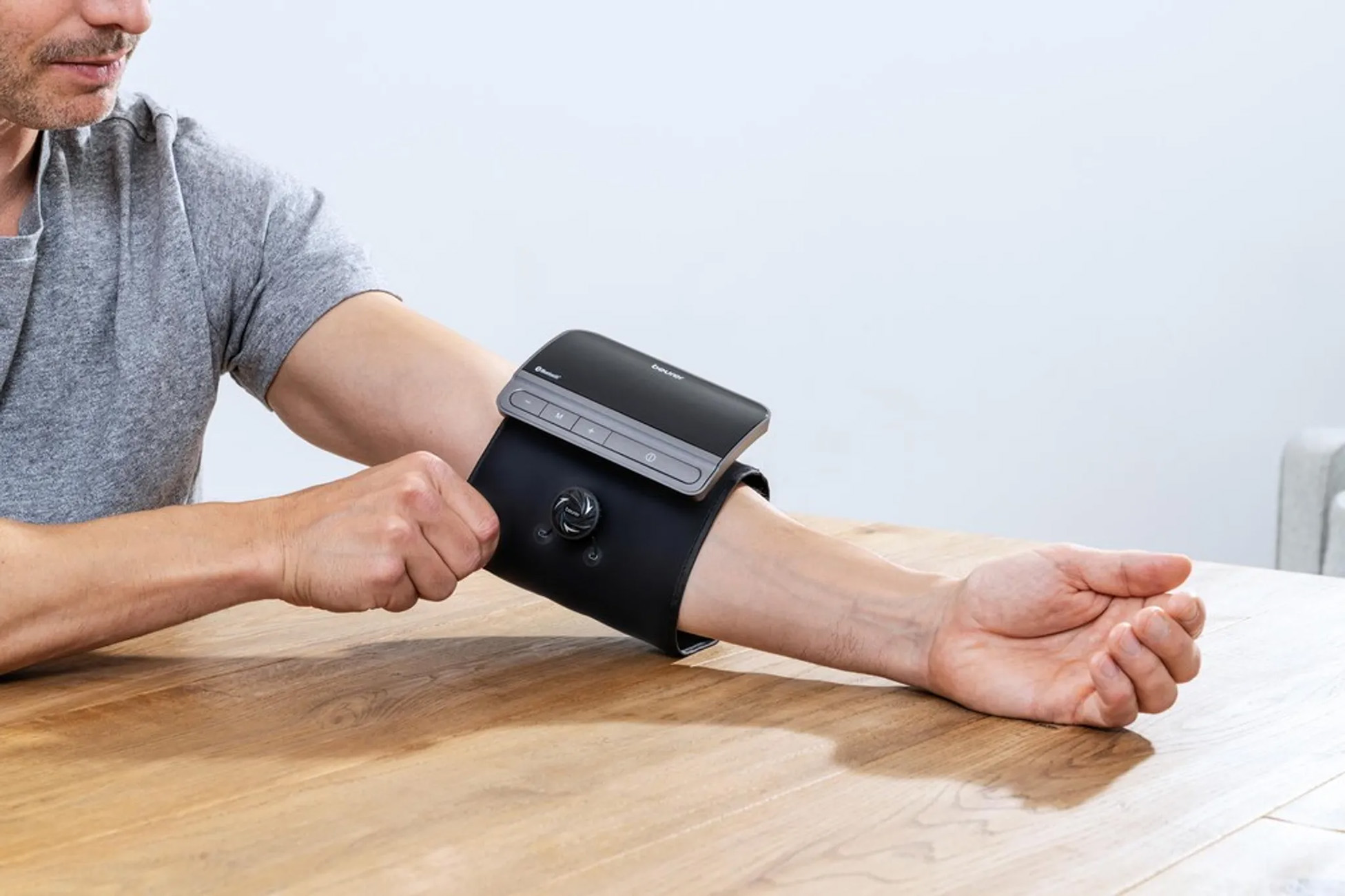 Ein Mann misst seinen Blutdruck mit einem Gerät an seinem Arm.