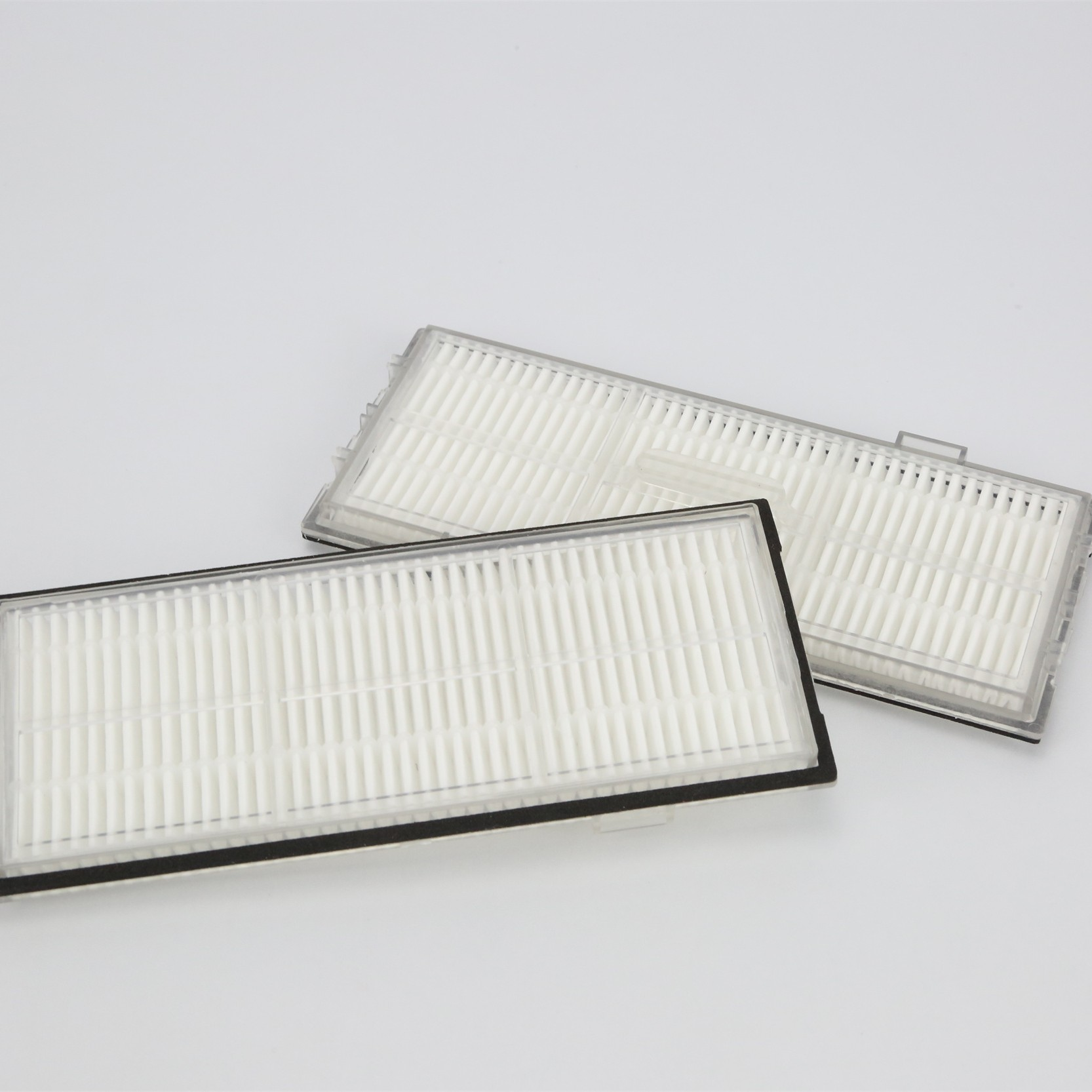 Dwa białe filtry do odkurzacza. Prostokątny kształt, z białym materiałem filtracyjnym w plastikowej ramie.