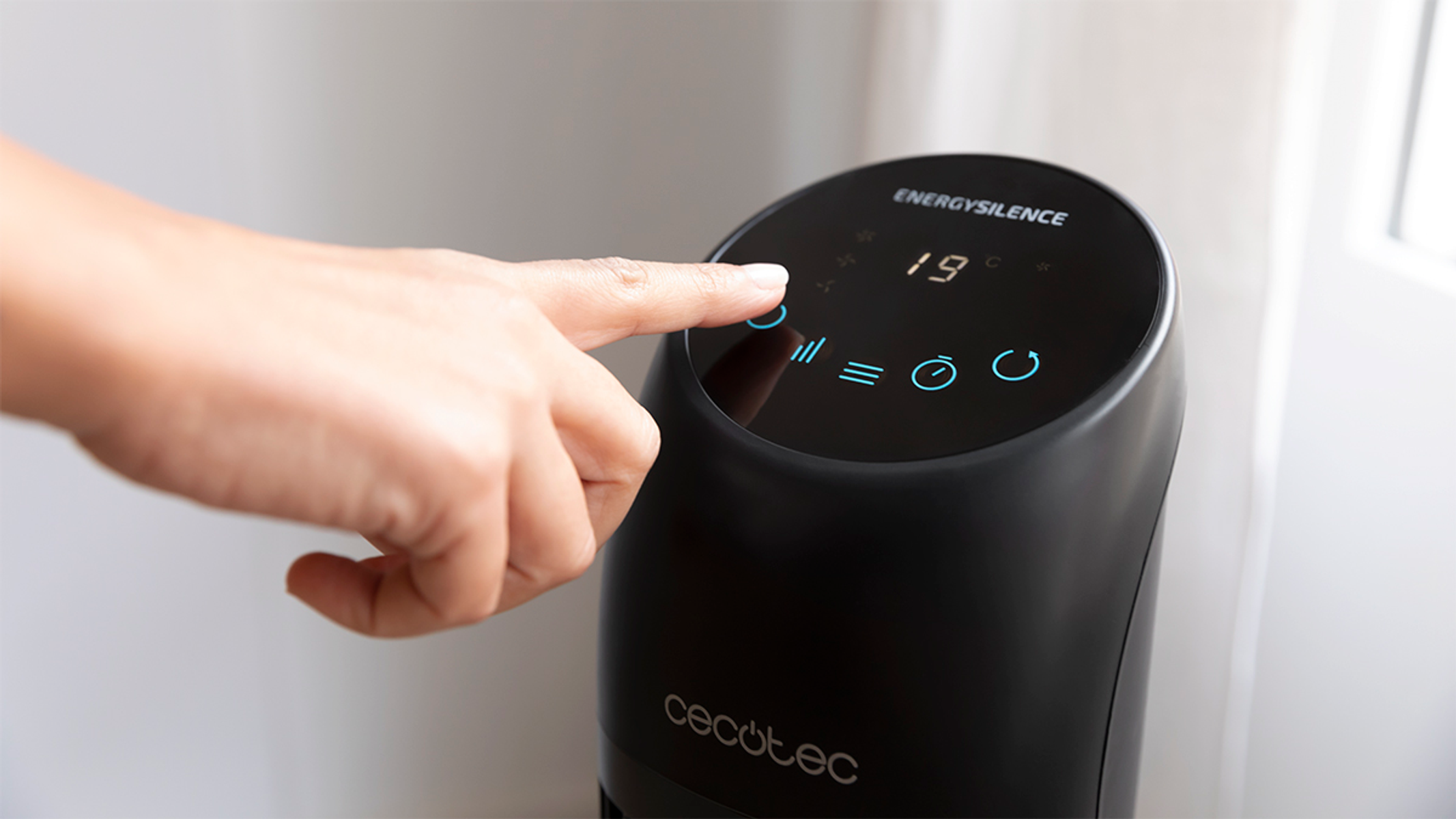Ręka naciskająca przycisk na czarnym oczyszczaczu powietrza.