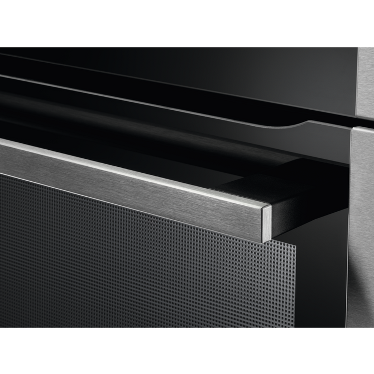 Zbliżenie czarnych drzwi piekarnika z perforowanym metalowym panelem i uchwytem.