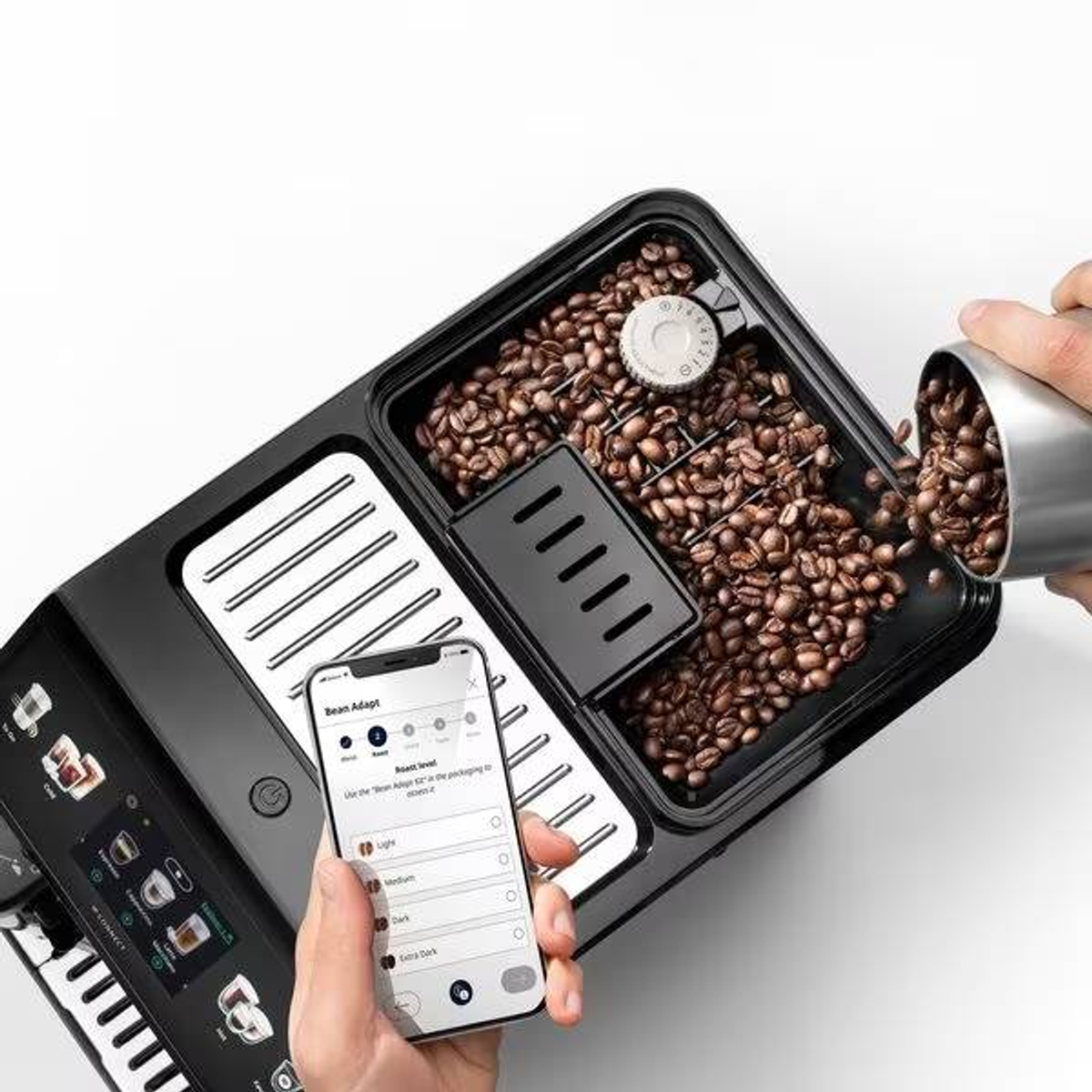 Macchina da caffè con chicchi, telefono con app e mano che versa i chicchi.