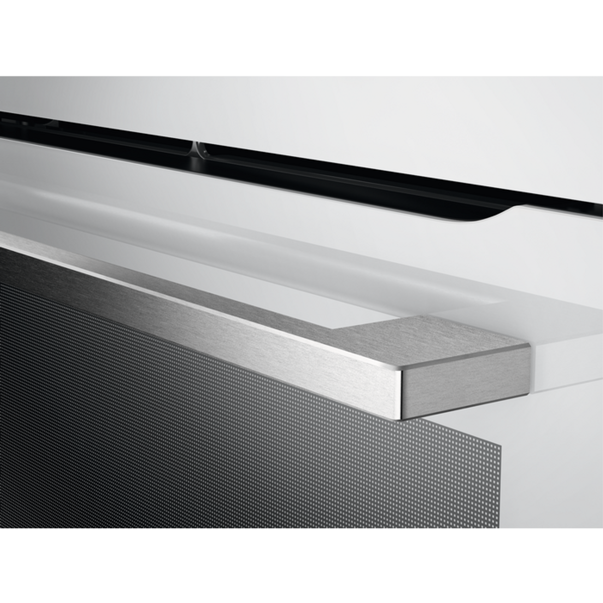 Primer plano de un tirador plateado en un electrodoméstico de cocina empotrado blanco y negro.