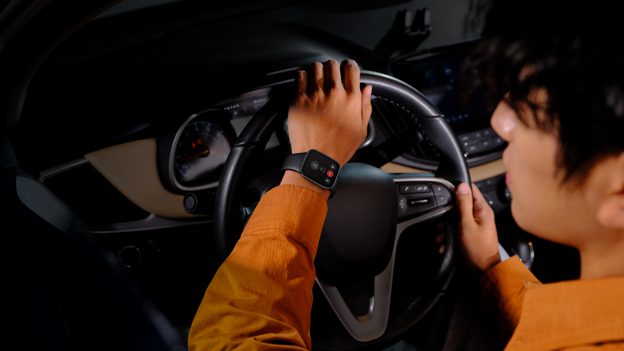 Persona con smartwatch in auto, tiene il volante, scena notturna.
