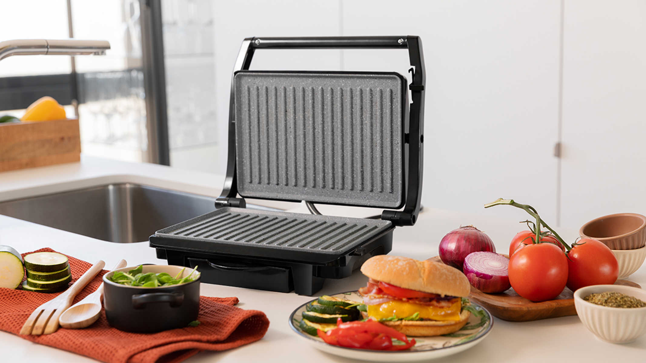 Prasa do kanapek z kanapką i składnikami. Białe tło kuchenne.