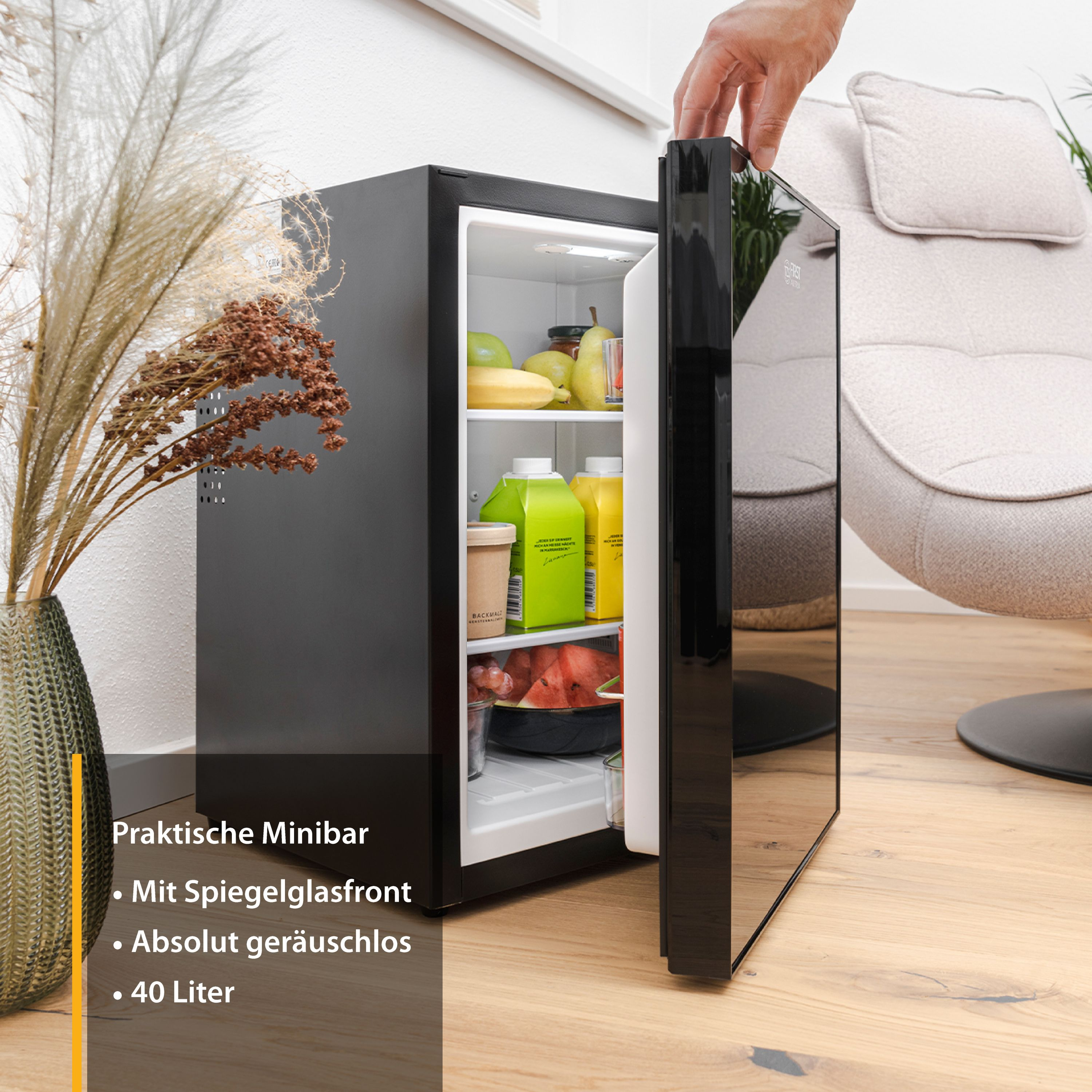 Mini réfrigérateur noir avec porte ouverte, divers aliments à l'intérieur. Fond blanc.
