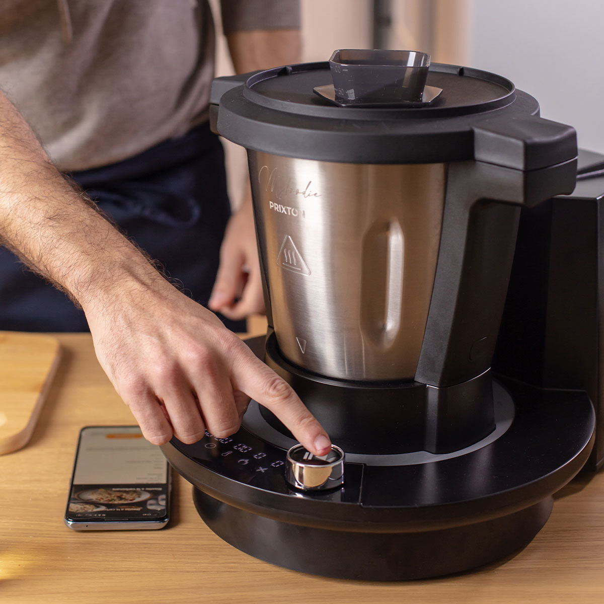 Osoba korzysta z urządzenia kuchennego. Urządzenie jest czarno-srebrne.