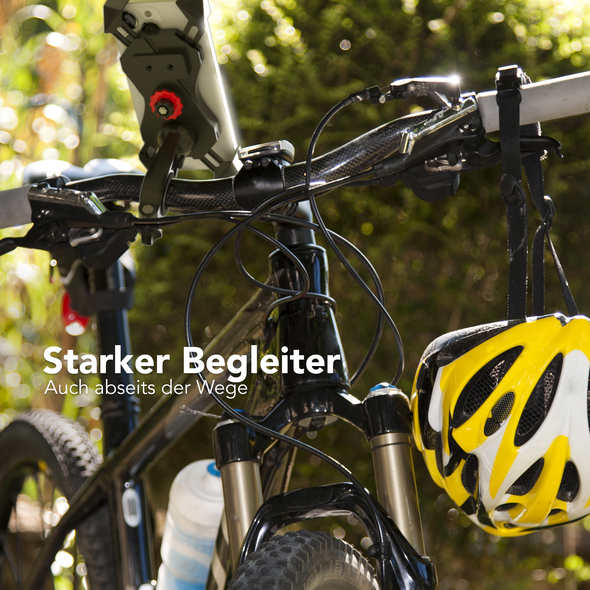 Fahrrad, Vorderansicht, mit Text. Helm hängt an der Seite. Grünes Laub im Hintergrund.
