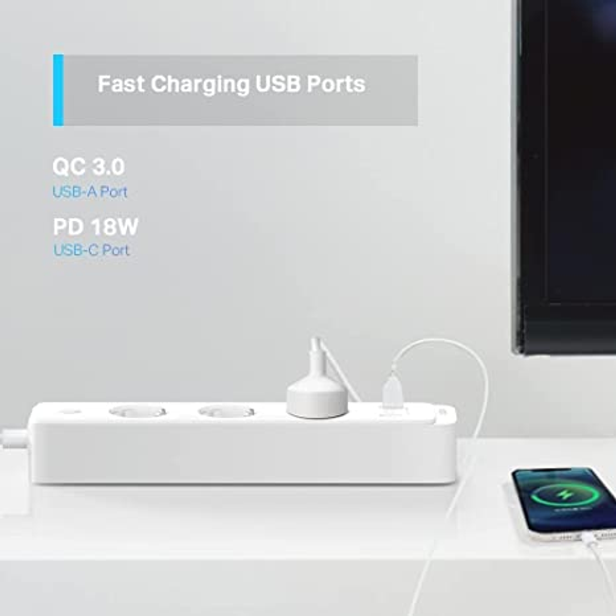 Eine weiße Steckdosenleiste mit drei Steckdosen, einem USB-A- und einem USB-C-Anschluss. Ein Telefon lädt auf einer weißen Oberfläche.