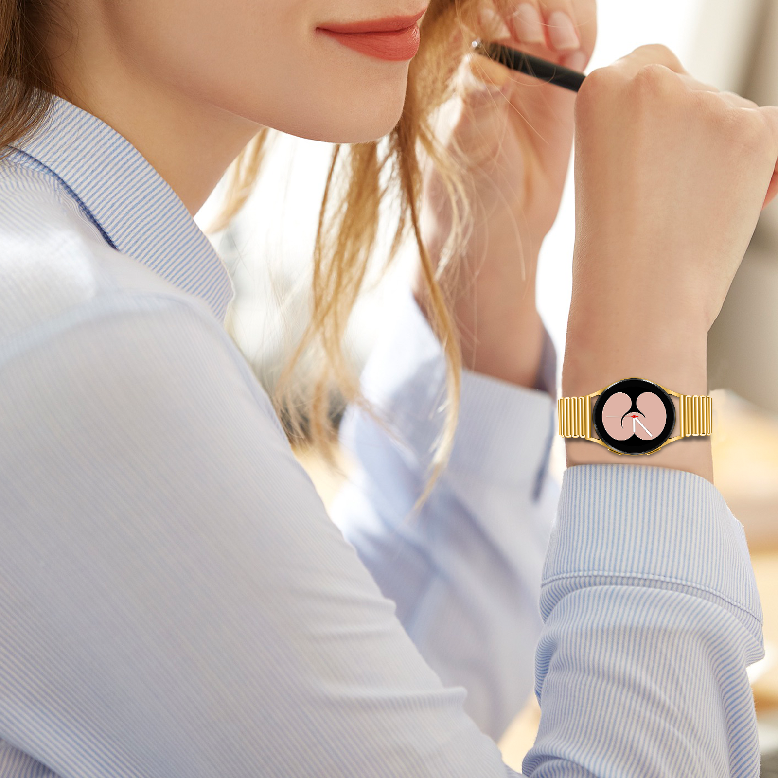 Eine Frau mit einer goldenen Uhr und einem goldenen Armband. Ihr Arm ist ausgestreckt, hält einen Stift.