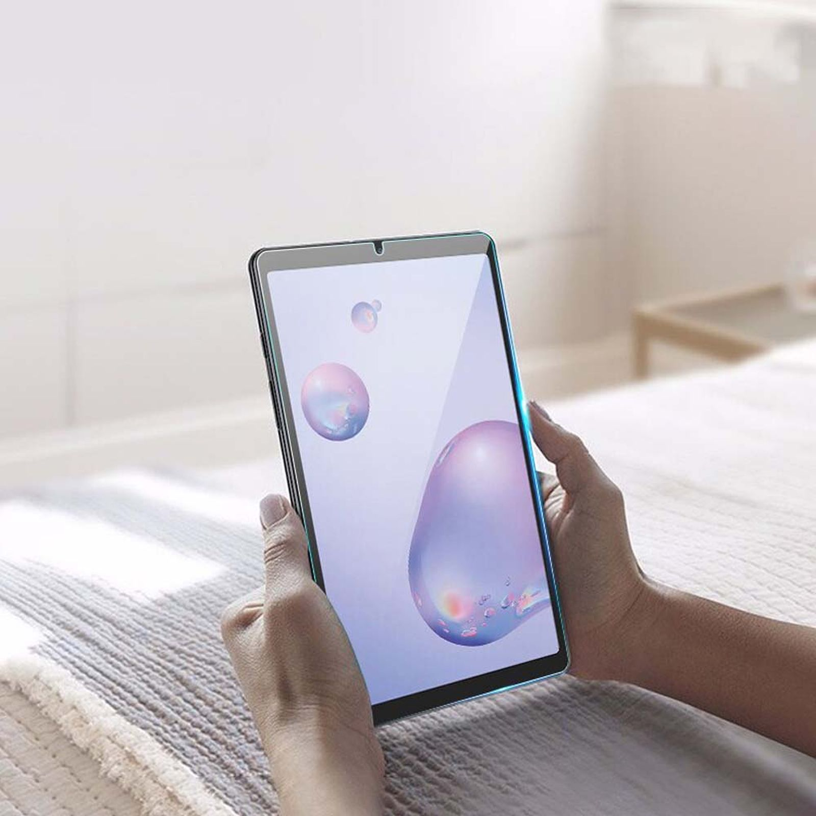 Persona che tiene un tablet. Il tablet ha una protezione schermo, che mostra uno sfondo viola e rosa.