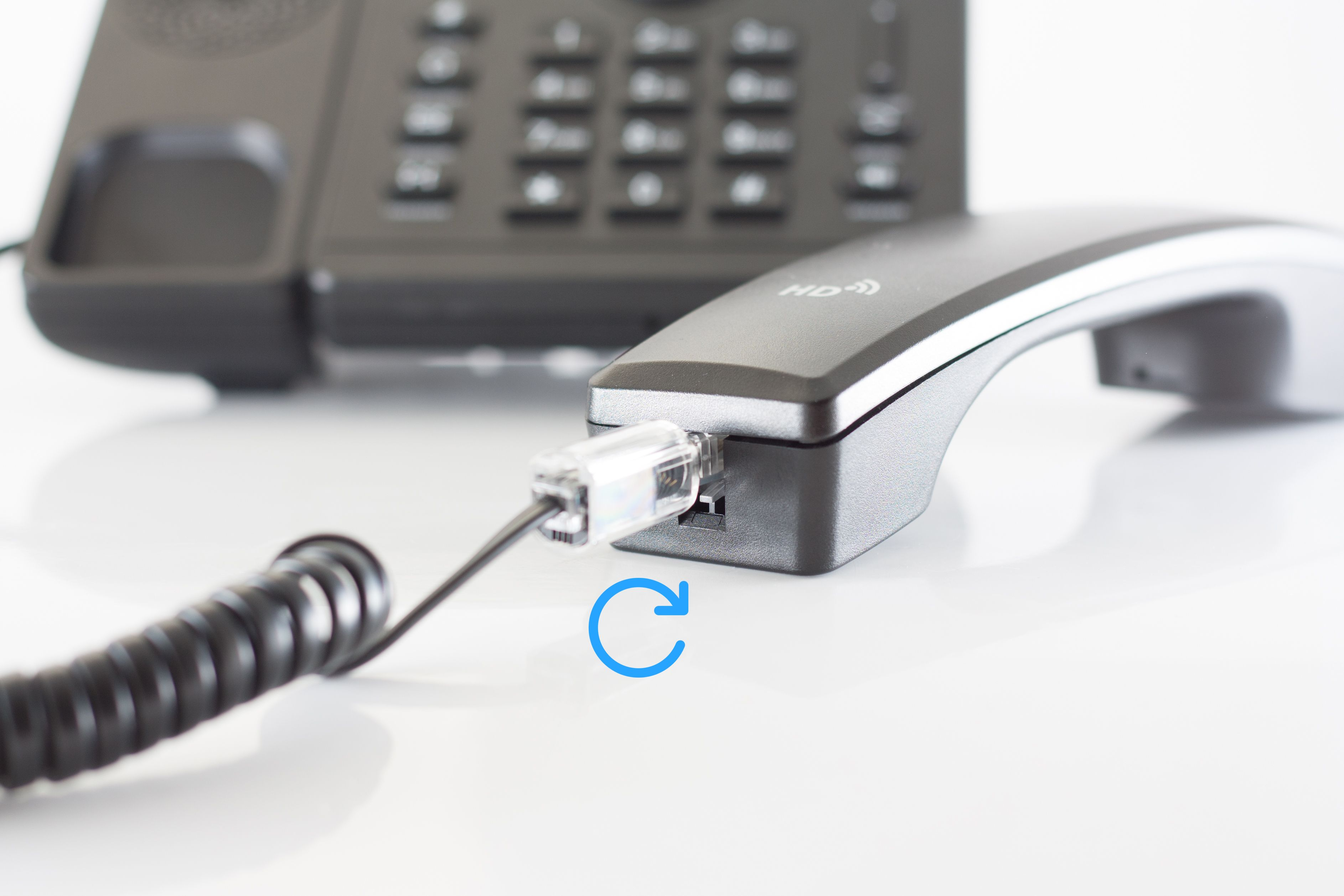 Telefon und Hörer mit Kabelanschluss und kreisendem Pfeil.