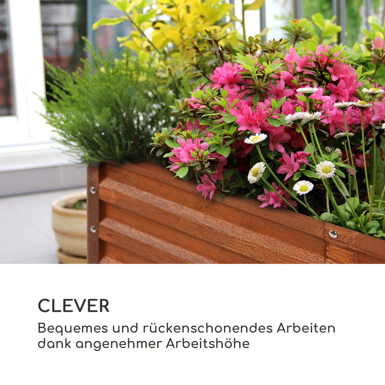 Una jardinera de madera con flores rosas y blancas, plantas verdes y texto debajo.