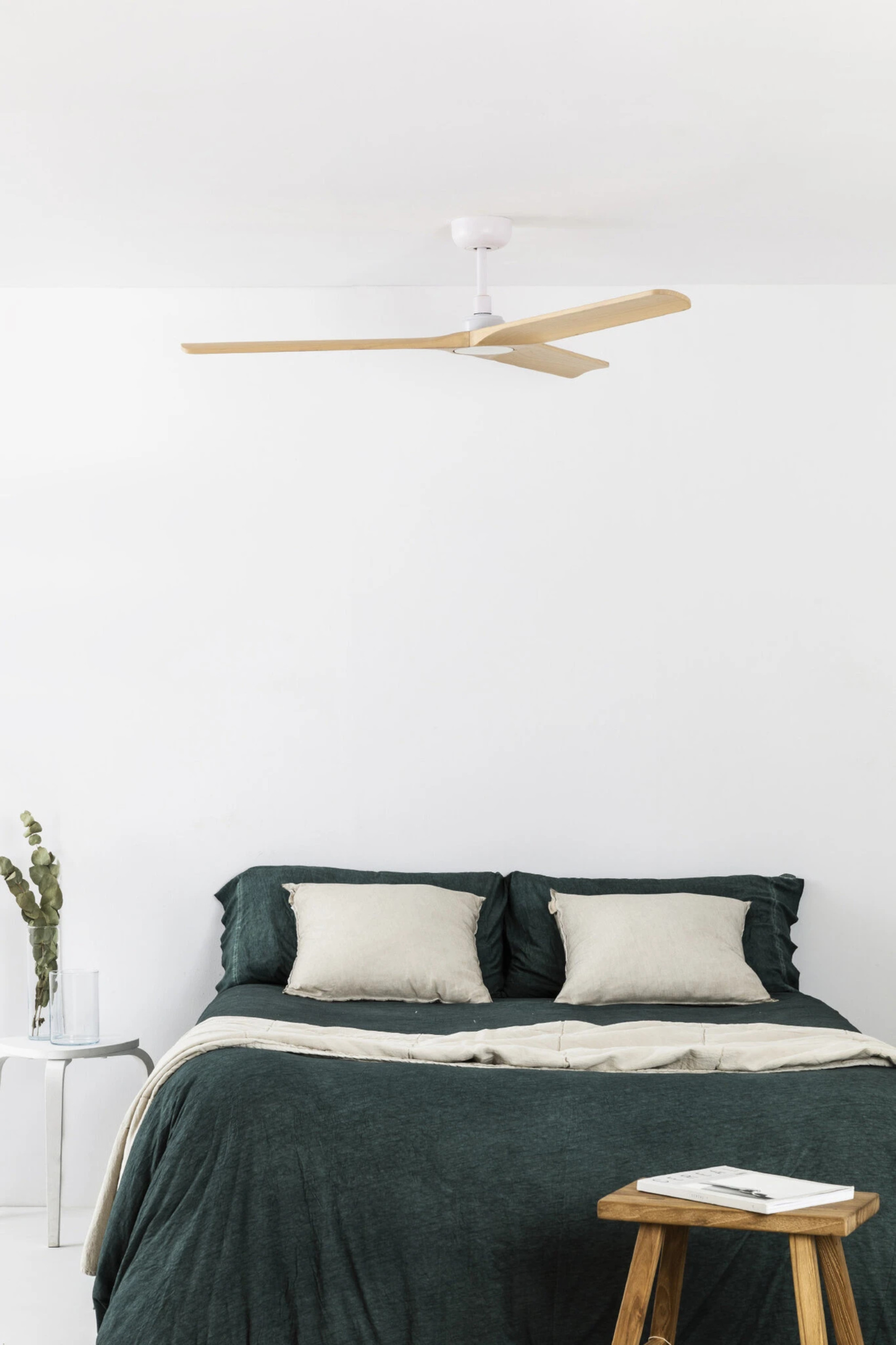 Schlafzimmer mit Bett, dunkelgrüner Bettdecke, weiße Wände.