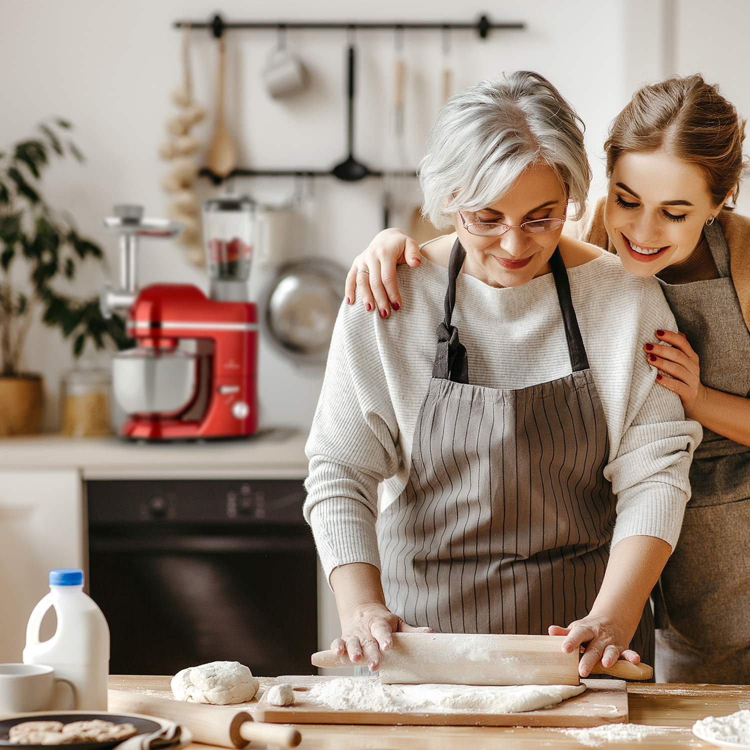 Zwei Frauen backen zusammen in der Küche, benutzen einen roten Mixer.