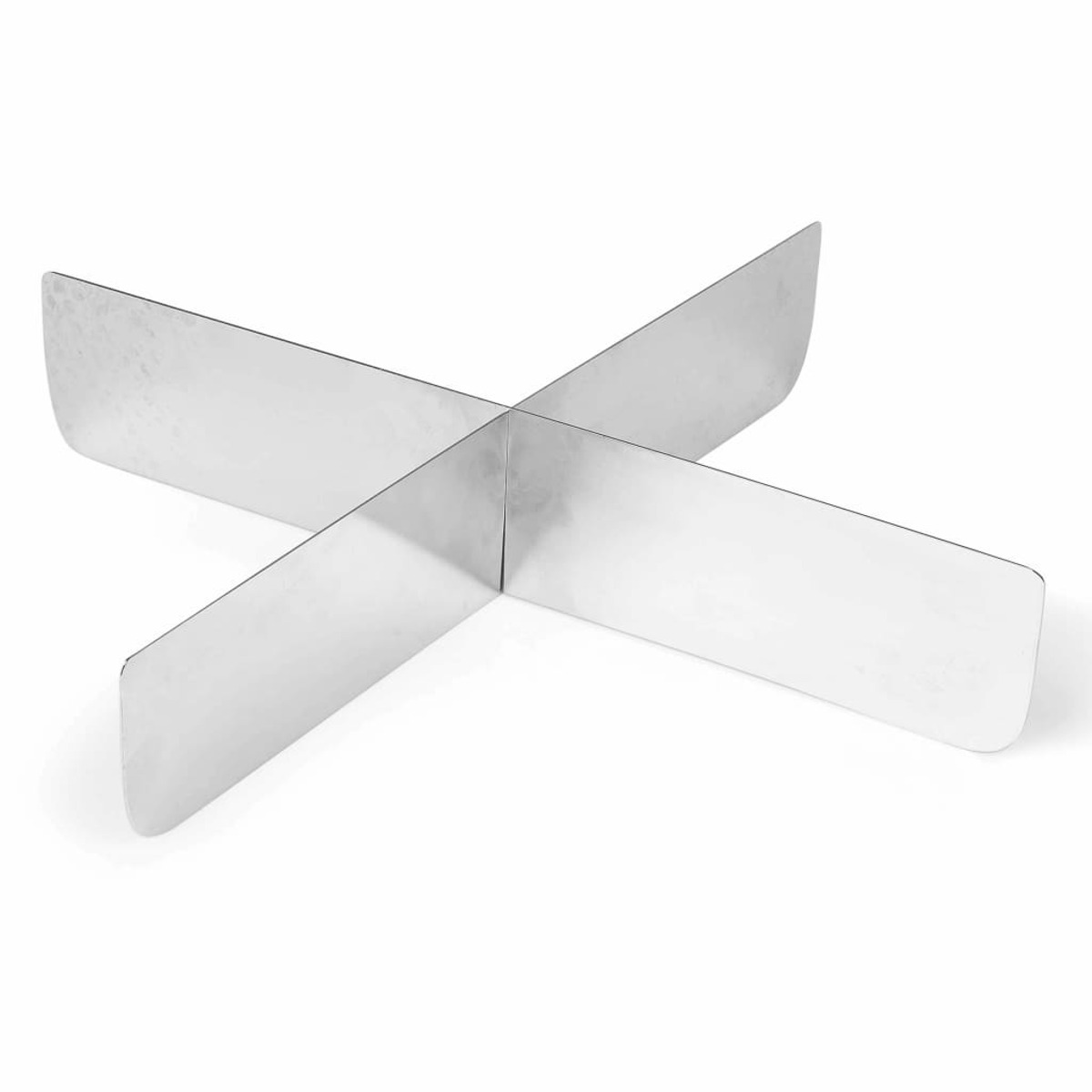 Ein metallischer kreuzförmiger Gegenstand auf einer weißen Oberfläche.