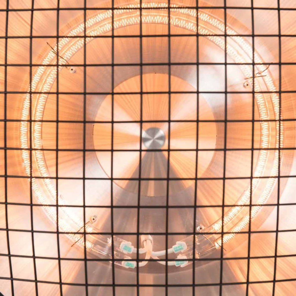 Close-up van een verwarmingselement. De achtergrond is oranje en de voorgrond een metalen rooster.