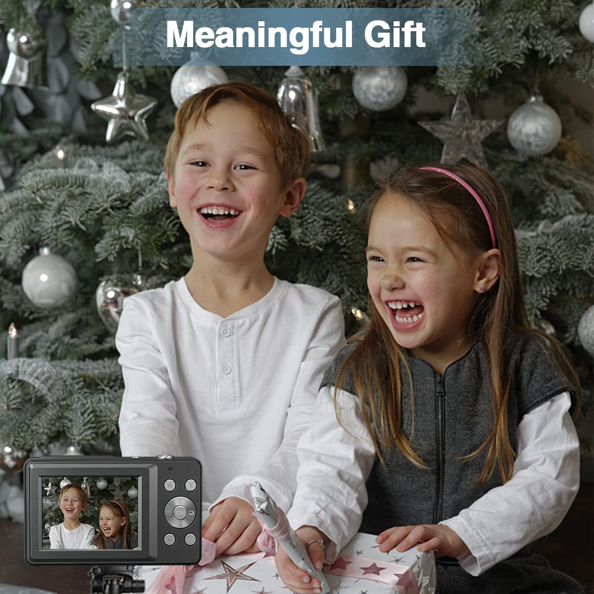 Dwoje śmiejących się dzieci patrzy na aparat fotograficzny w pobliżu choinki.