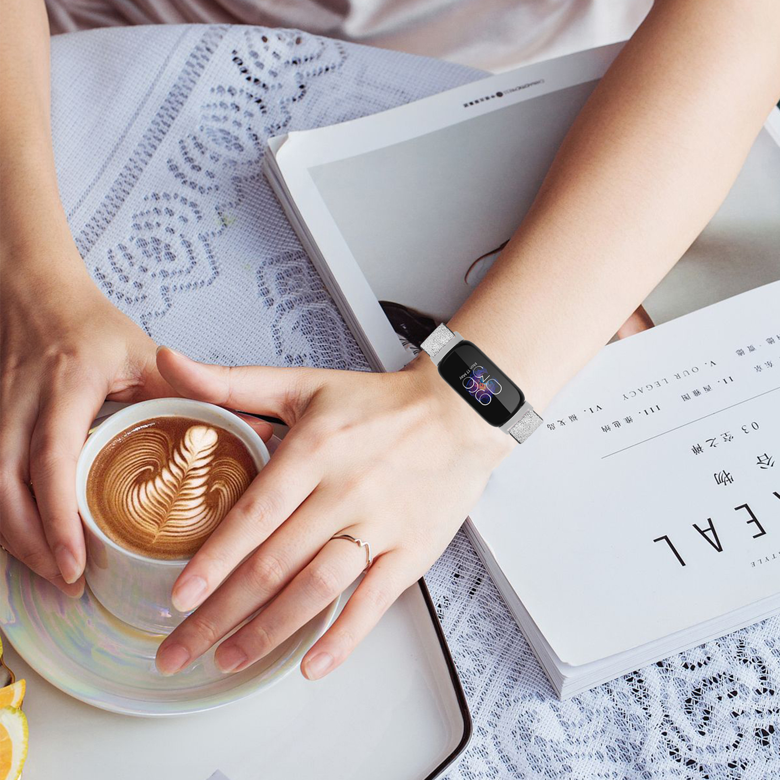 Ein Handgelenk mit einer Smartwatch und einer Kaffeetasse auf einem Magazin, das eine gemütliche Umgebung zeigt.