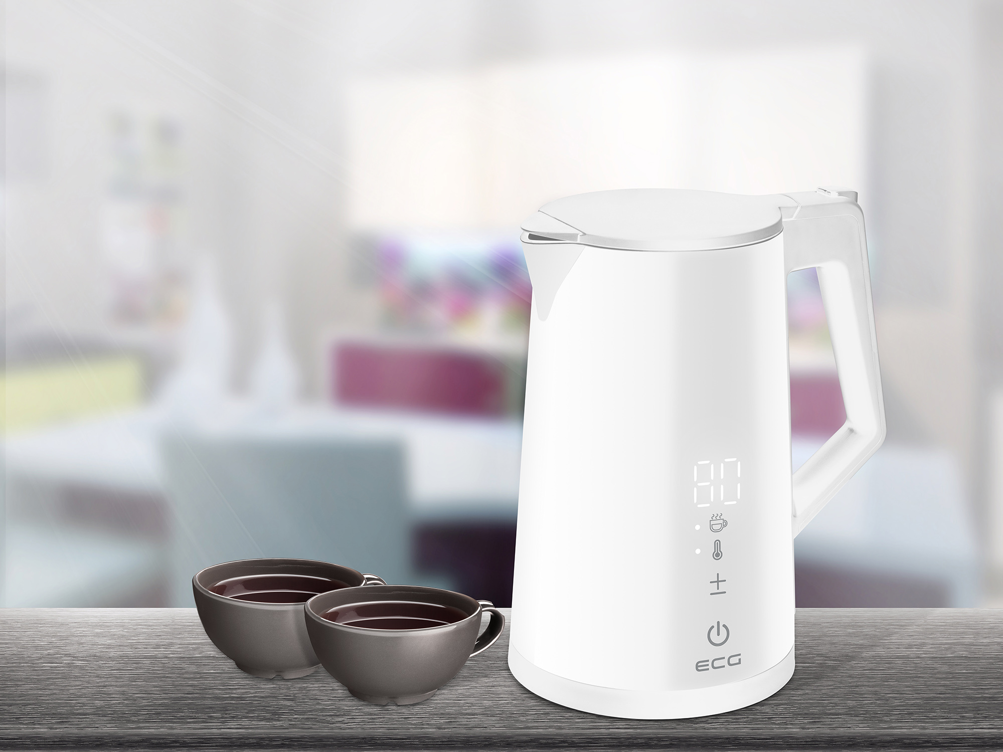 Biały czajnik elektryczny z dwiema filiżankami herbaty. Tło to rozmyta scena wnętrza.