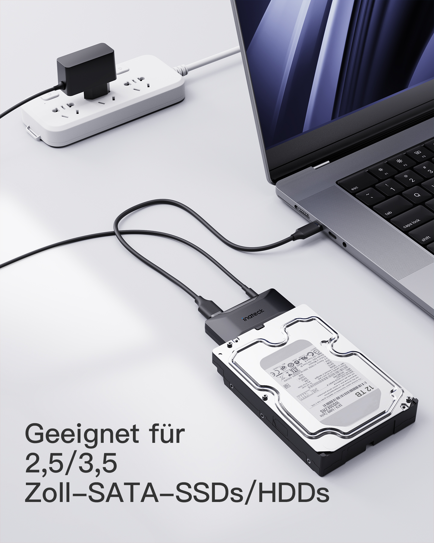 Ein Laptop, der über einen USB-Adapter und einen Netzadapter mit einer Festplatte verbunden ist.