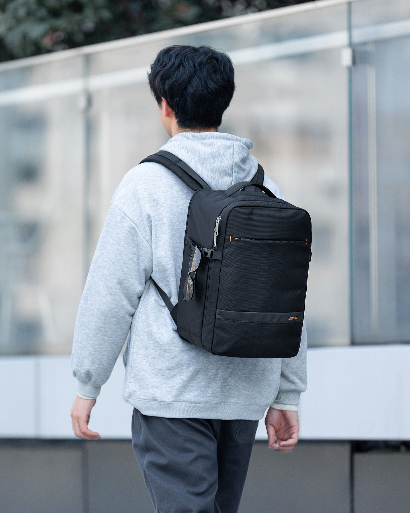 Mann mit schwarzem Rucksack geht. Der Rucksack ist schwarz mit einer Tasche und hängenden Gläsern.