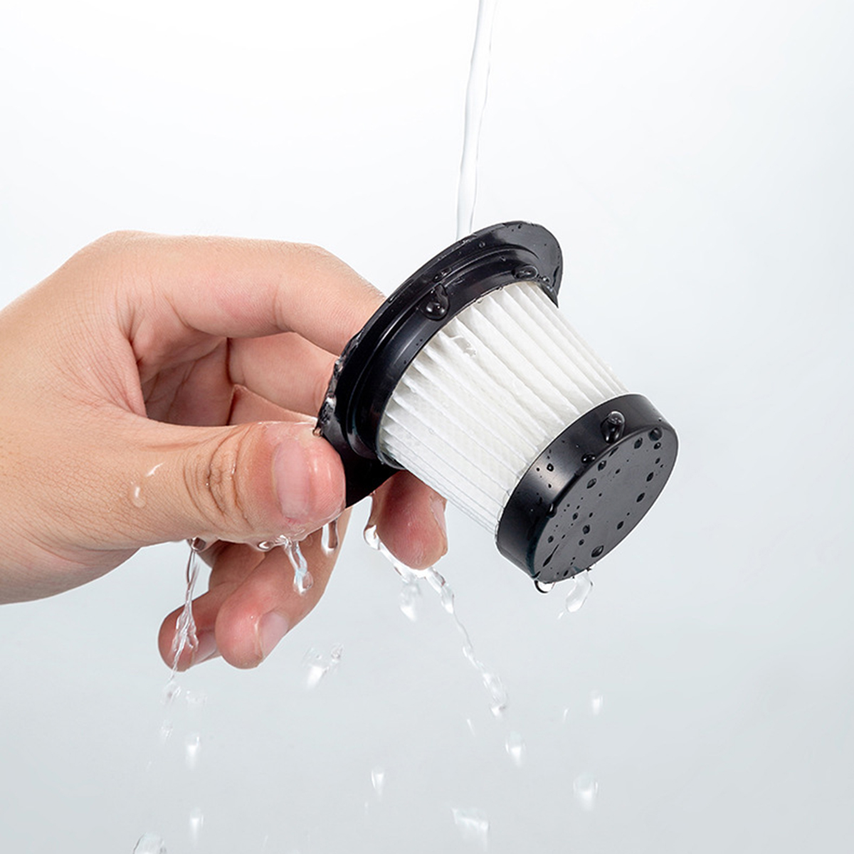 Una mano sosteniendo un filtro de vacío bajo agua corriente para limpiar.
