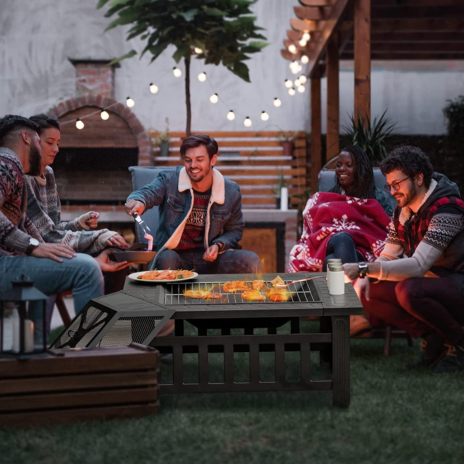 Gruppe von Leuten um einen Grilltisch, grillen Essen. Hintergrund hat Lichter und einen Ziegelbogen.