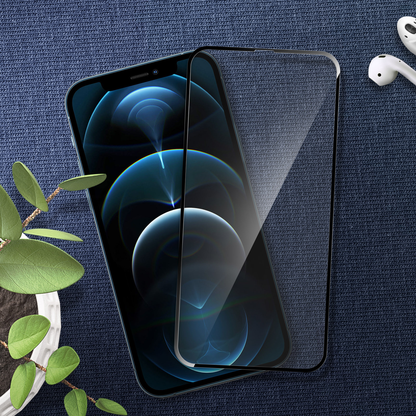 Uno smartphone con protezione schermo, AirPods e una piccola pianta su uno sfondo blu strutturato.