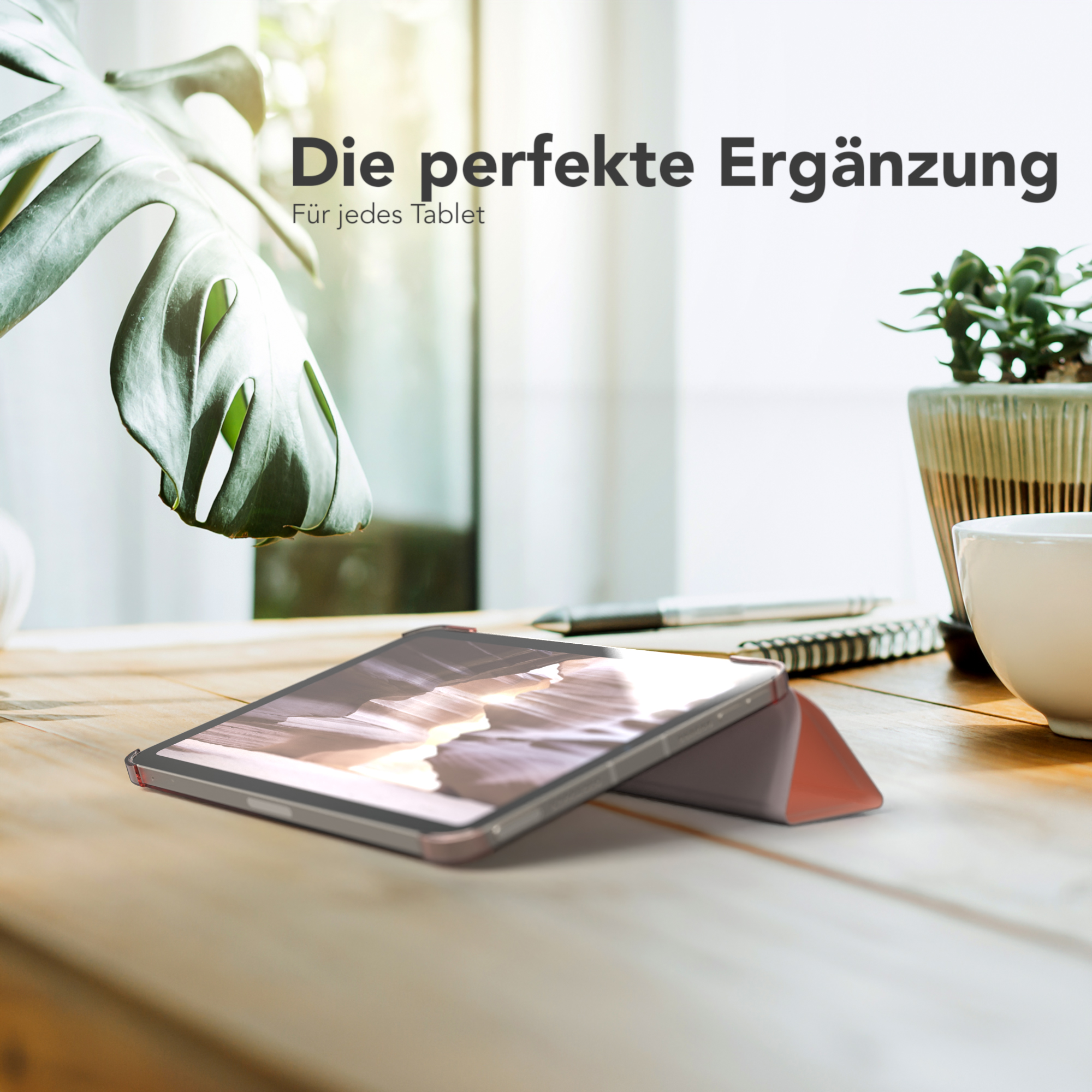 Ein Tablet in einer Hülle auf einem Holztisch, Pflanze und Fenster im Hintergrund.