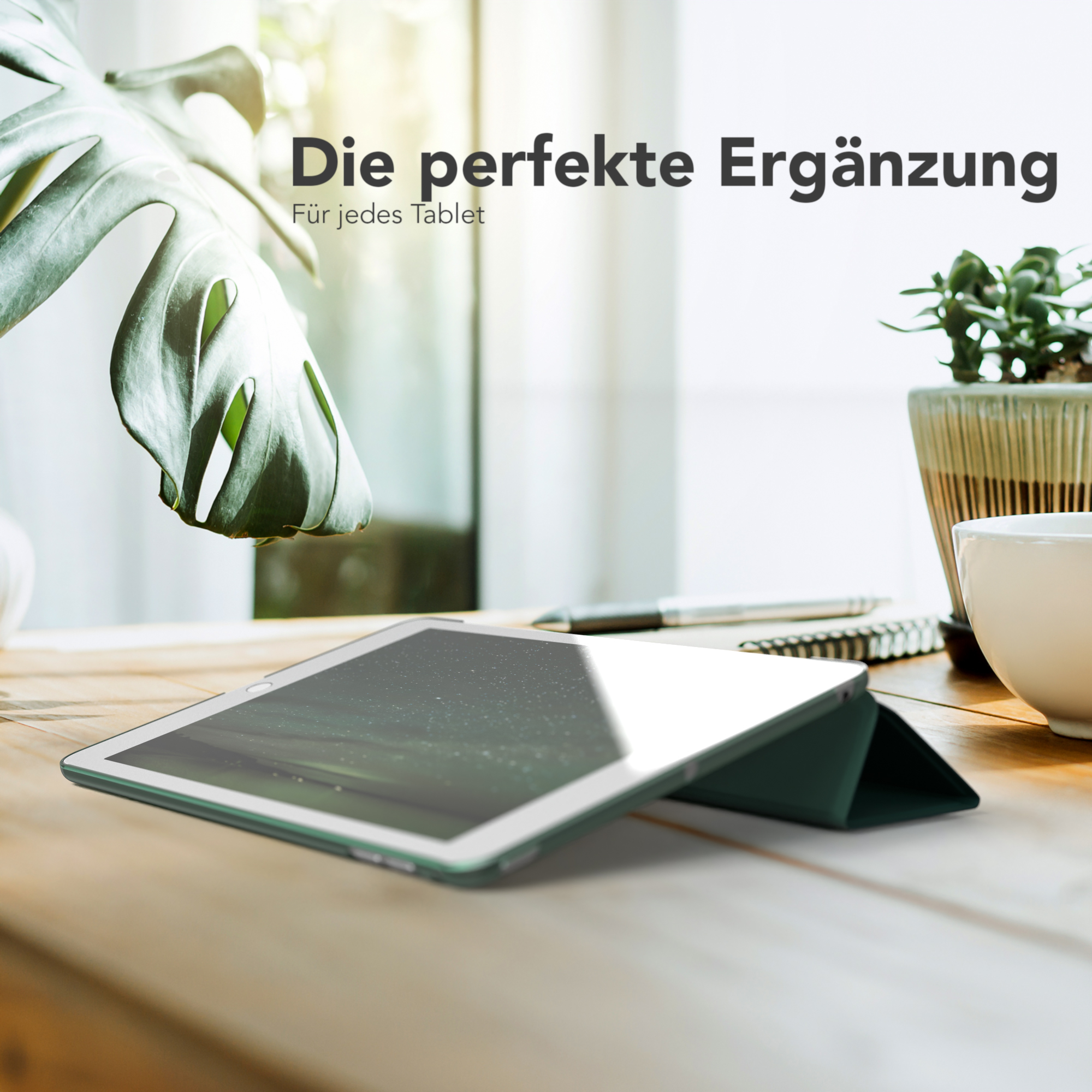 Ein Tablet auf einem Holztisch mit einer Pflanze und einer Tasse.