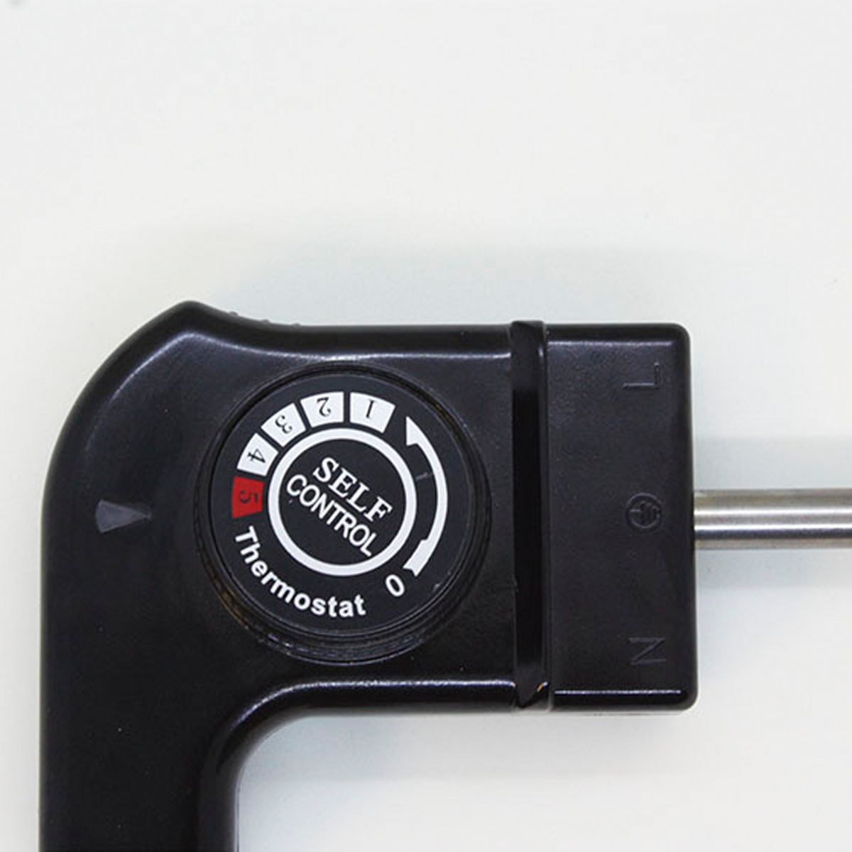 Schwarzer Thermostatregler mit Zahlen 0-5, beschriftet mit Self Control Thermostat. Auf weißer Oberfläche.