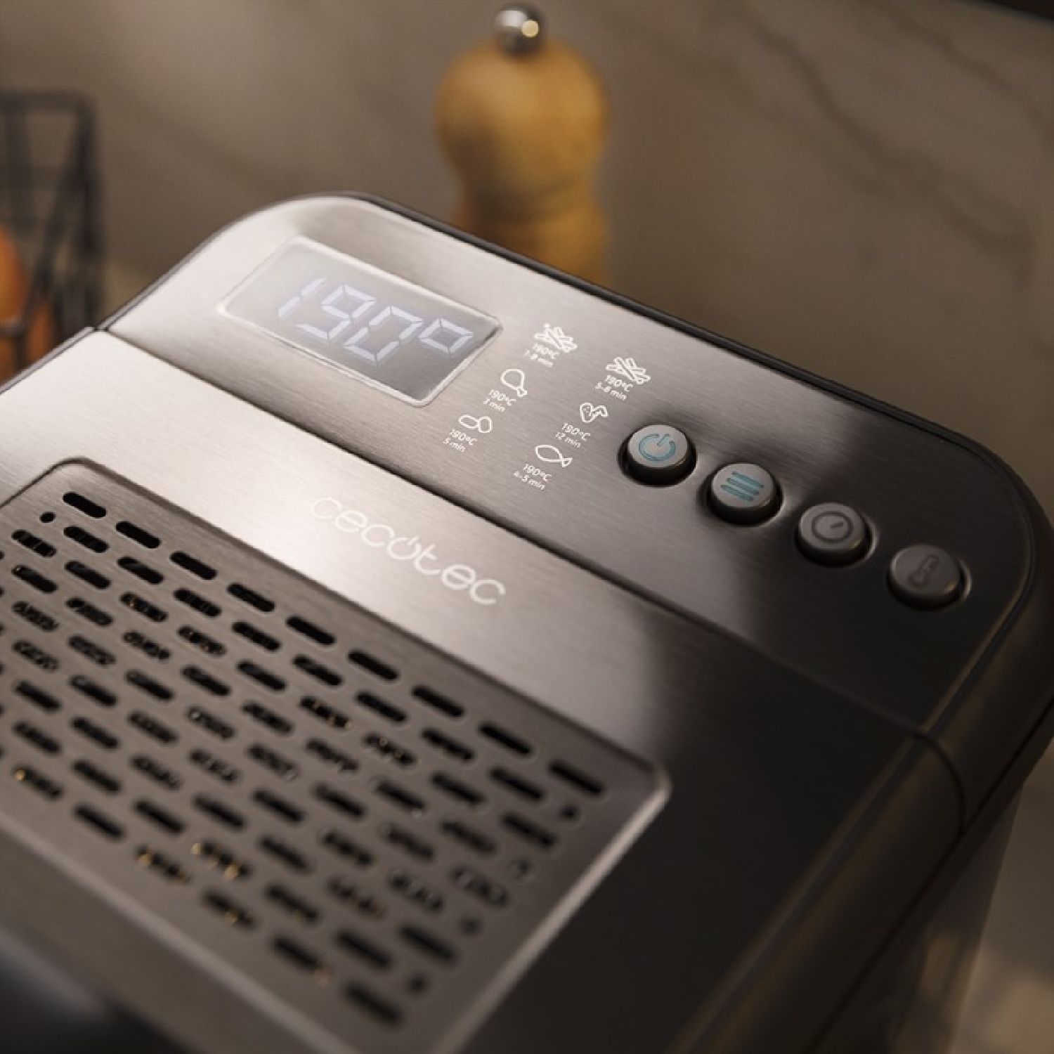 Zbliżenie panelu sterowania frytkownicy powietrznej z cyfrowym wyświetlaczem, przyciskami i ikonami. Urządzenie jest ciemnoszare.