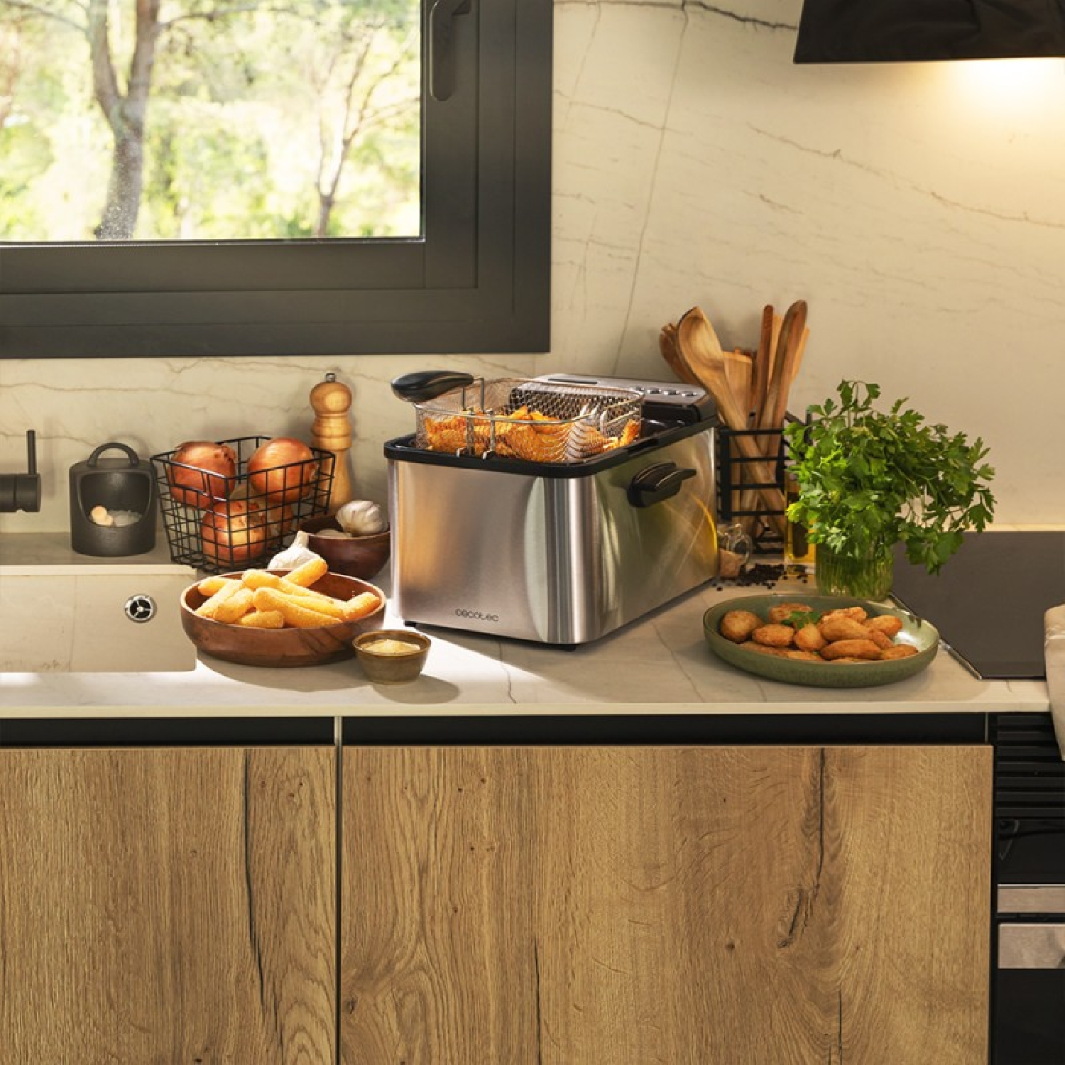 Scena kuchenna z frytkownicą, drewnianymi miskami i składnikami na blacie.