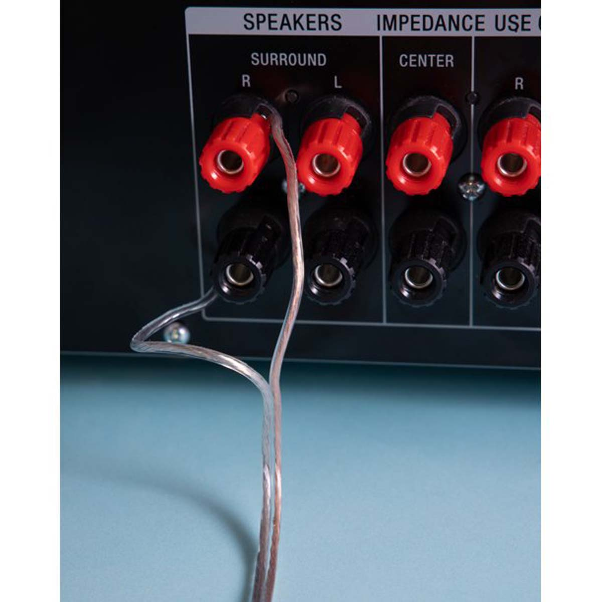 Nahaufnahme von Audio-Receiver-Anschlüssen. Rote und schwarze Klemmen mit Lautsprecherkabel. Blauer Hintergrund.