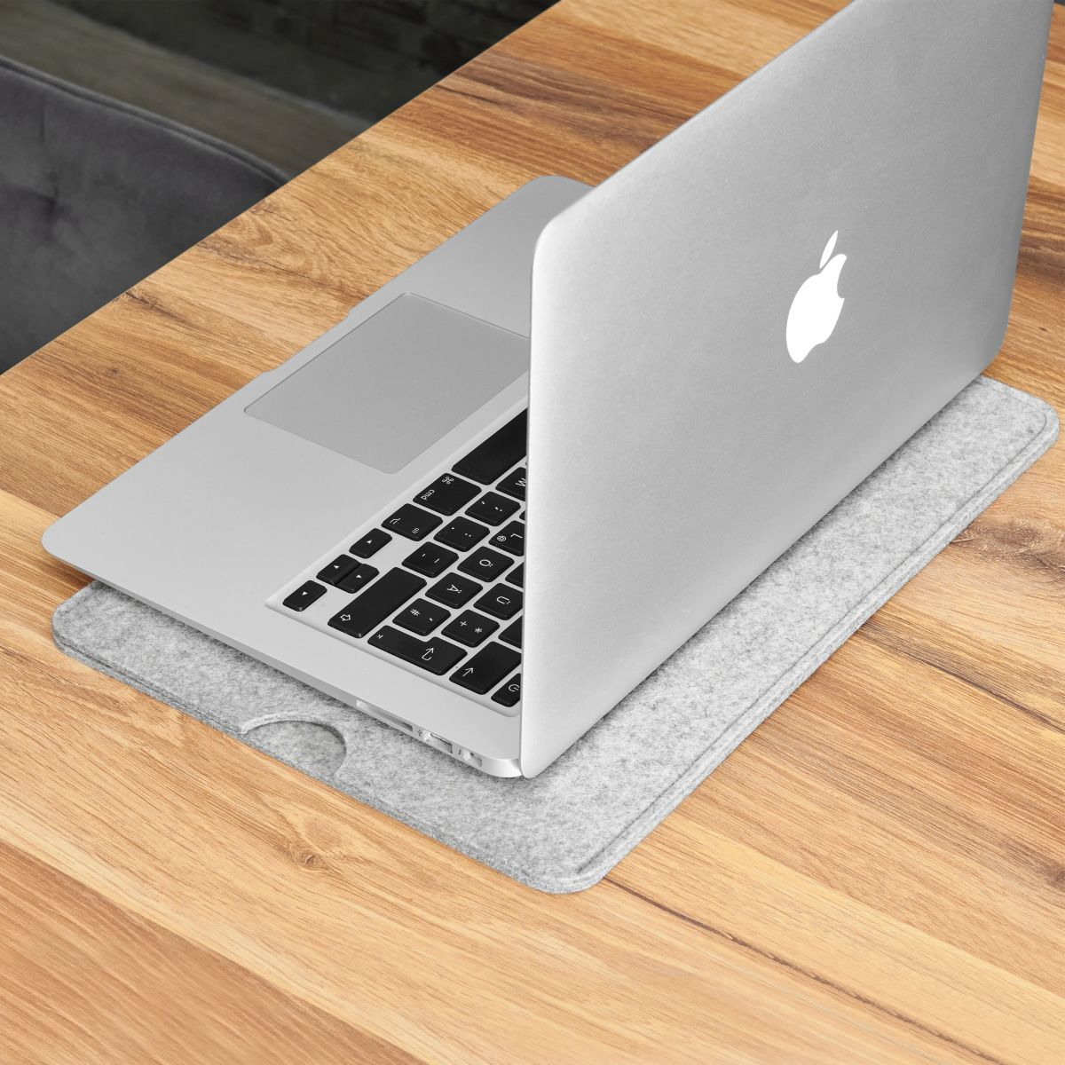 Laptop offen auf einem Filzpad auf einem Holztisch.