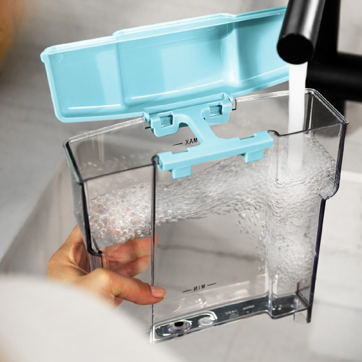 Ein klarer Plastik-Wassertank, der mit Wasser aus einem Wasserhahn gefüllt wird.