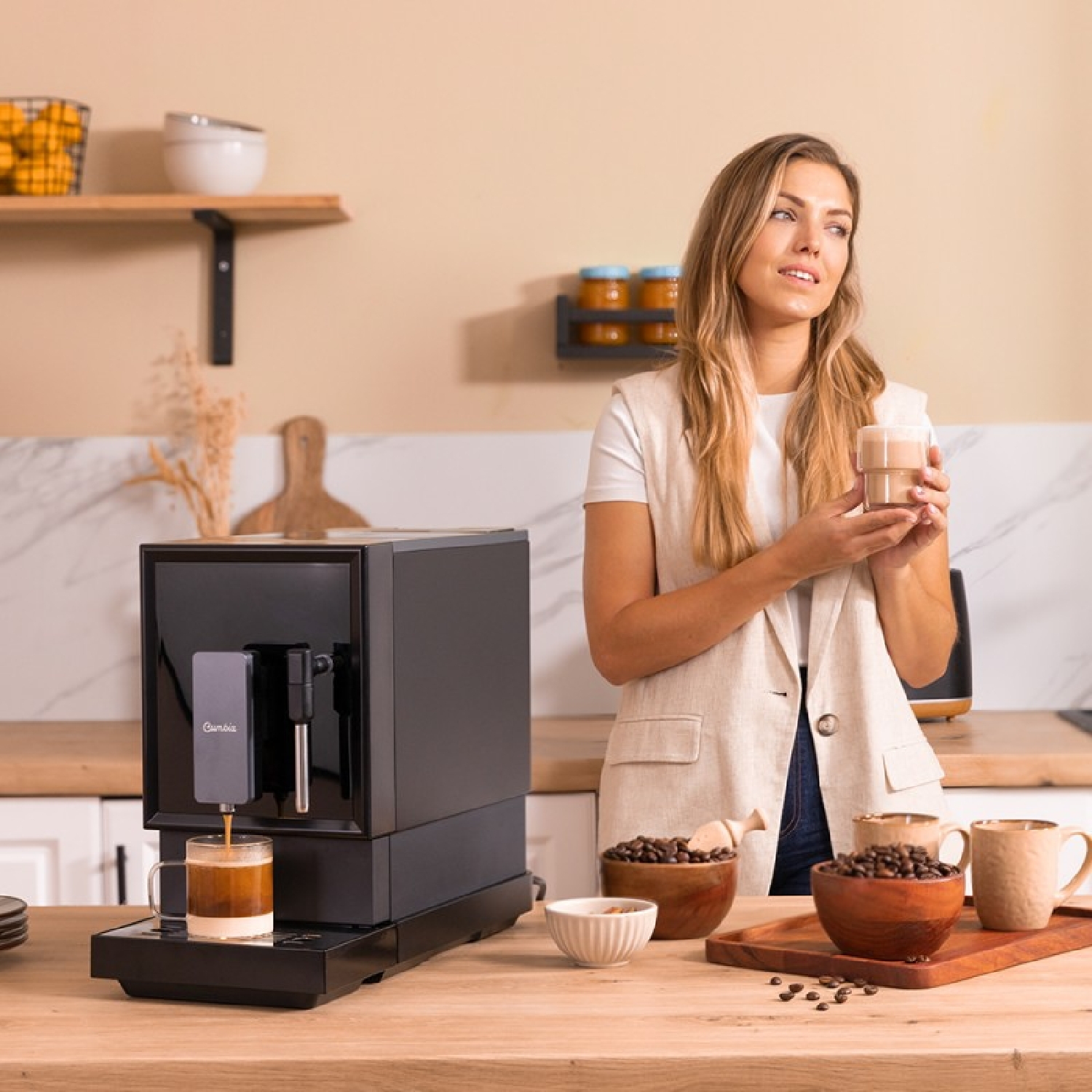 Mujer preparando café con una cafetera negra, cerca de granos y tazas.