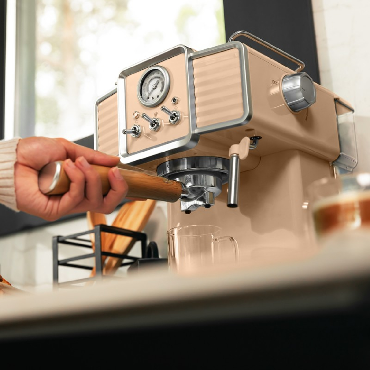 Una macchina per caffè espresso beige con la mano di una persona che tiene un manico di legno.