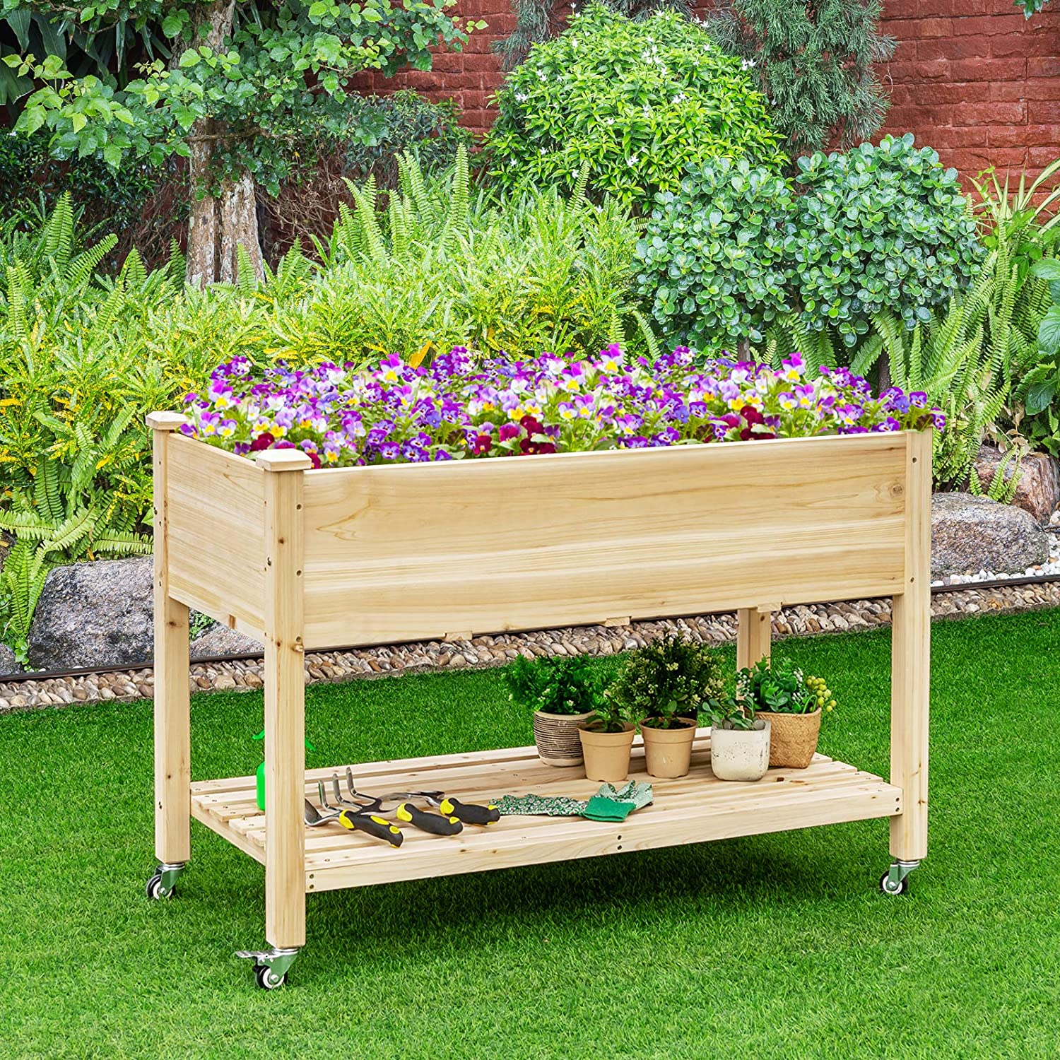Ein erhöhter Gartenbeetwagen aus Holz, gefüllt mit bunten Blumen und Pflanzen. In einem Garten aufgestellt.