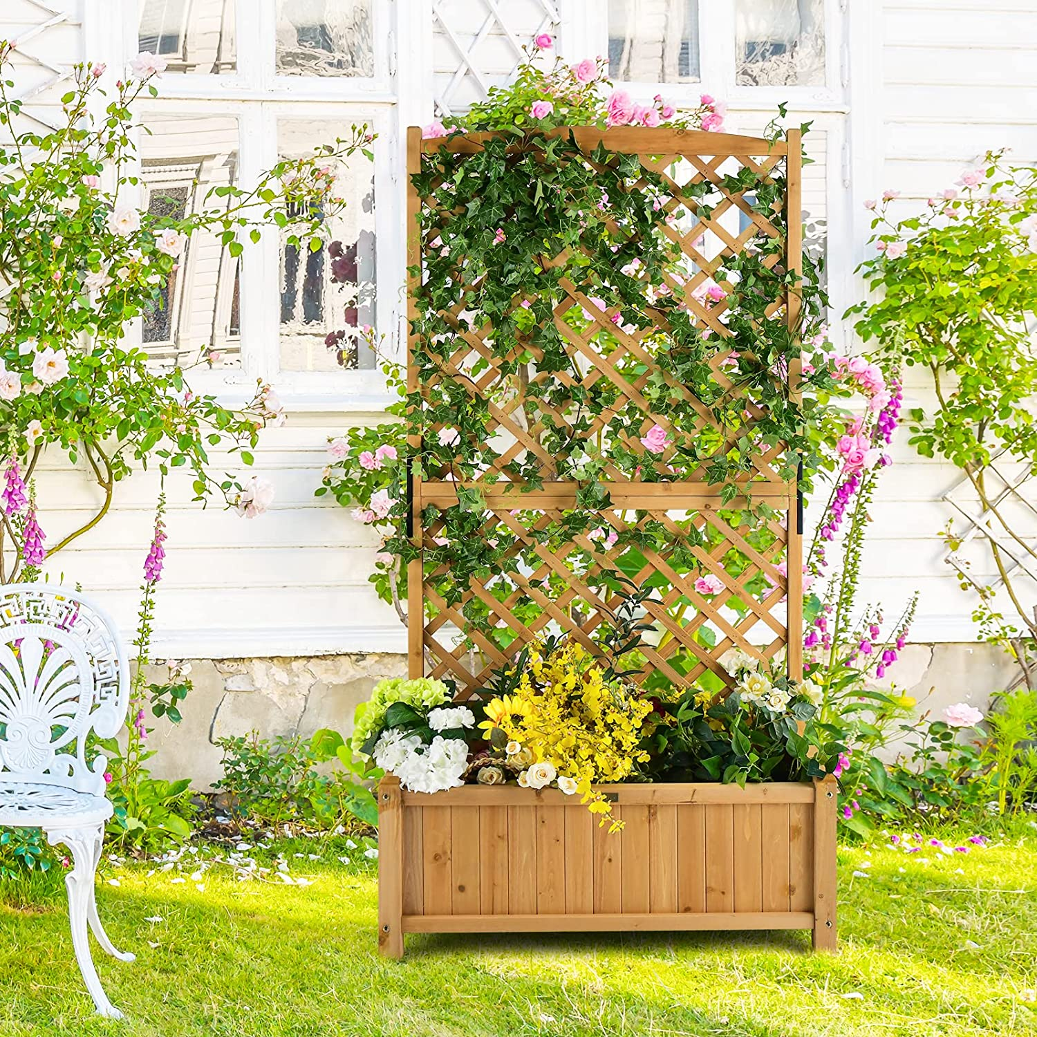 Ein hölzerner Gartenpflanzer mit Spalier. Er enthält rosa Rosen, grüne Blätter und andere Blumen.