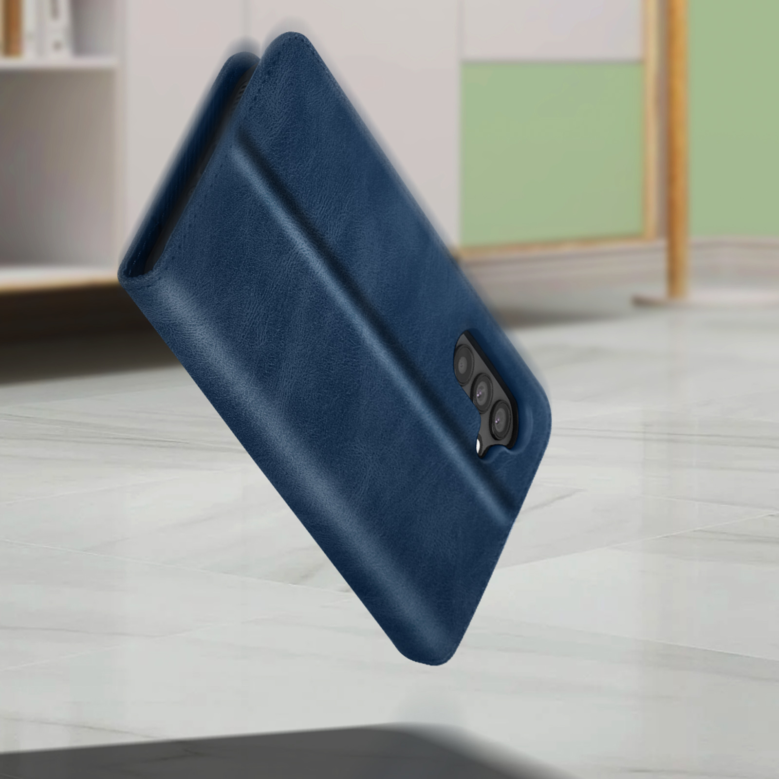 Blauwe leren telefoonhoes, staand op een oppervlak. Camera-uitsparingen zichtbaar. Achtergrond is wazig.