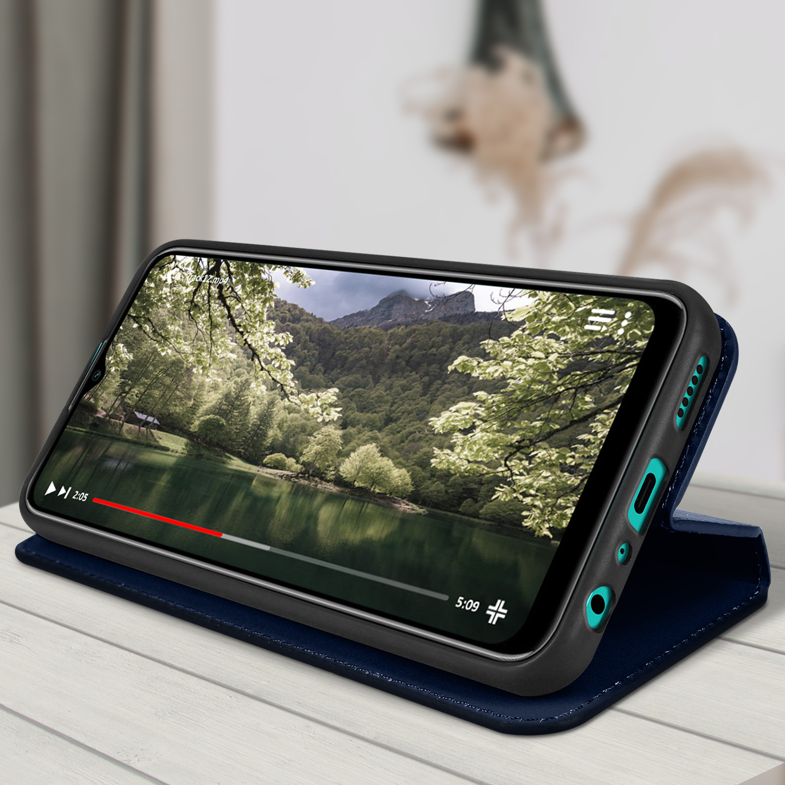 Smartphone in een blauwe hoes, speelt een video van een meer en bomen af. De tijdlijn is zichtbaar.