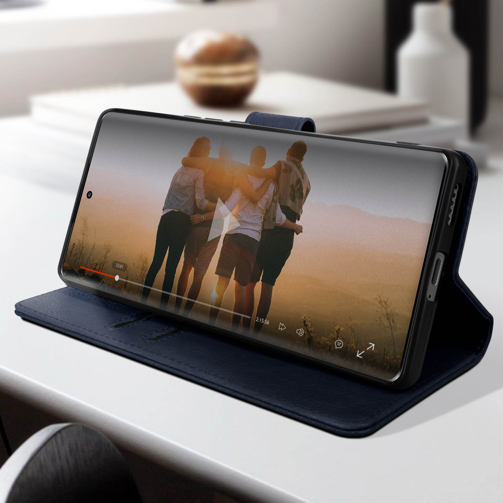 Smartphone che mostra un video di un gruppo di persone. Il telefono è in una custodia blu su un tavolo.