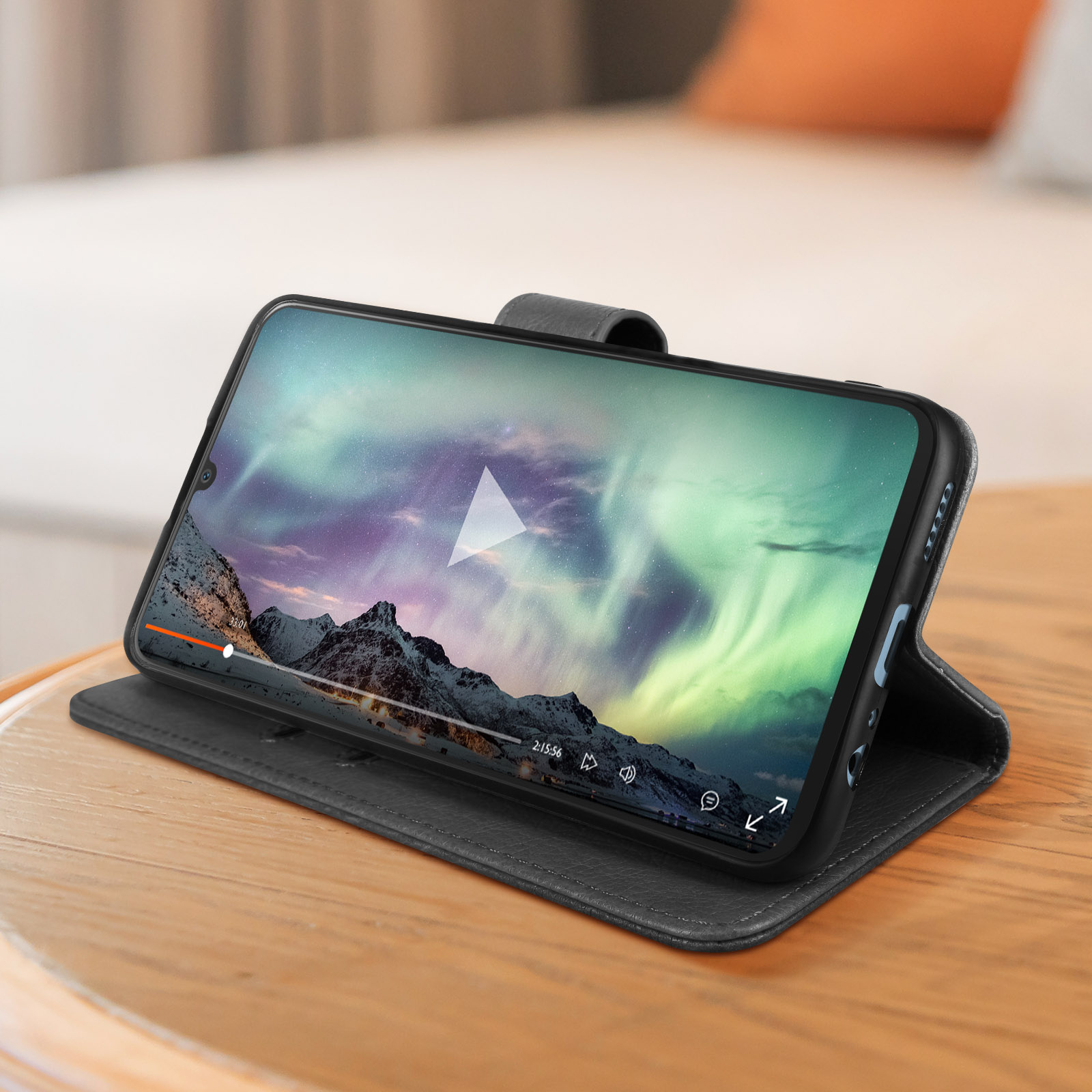 Uno smartphone su un tavolo di legno, in una custodia che mostra un video dell'aurora boreale, in riproduzione.